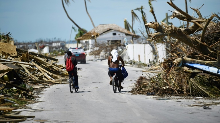 Des habitants de Marsh Harbour à vélo au milieu des dégâts provoqués par le passage de l'ouragan Dorian, le 5 septembre 2019 aux Bahamas.
