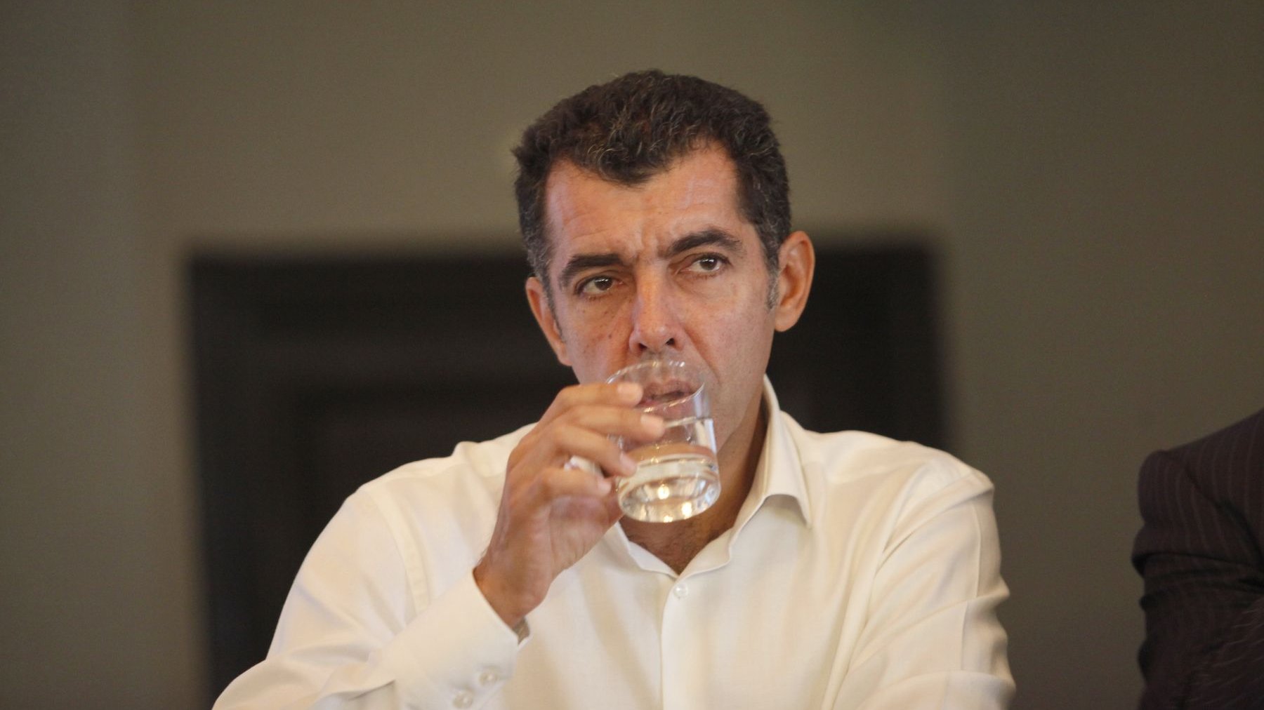 Adil Douiri, sérieux et pensif, semble en avoir oublié le verre d'eau qu'il tient entre ses doigts. 
