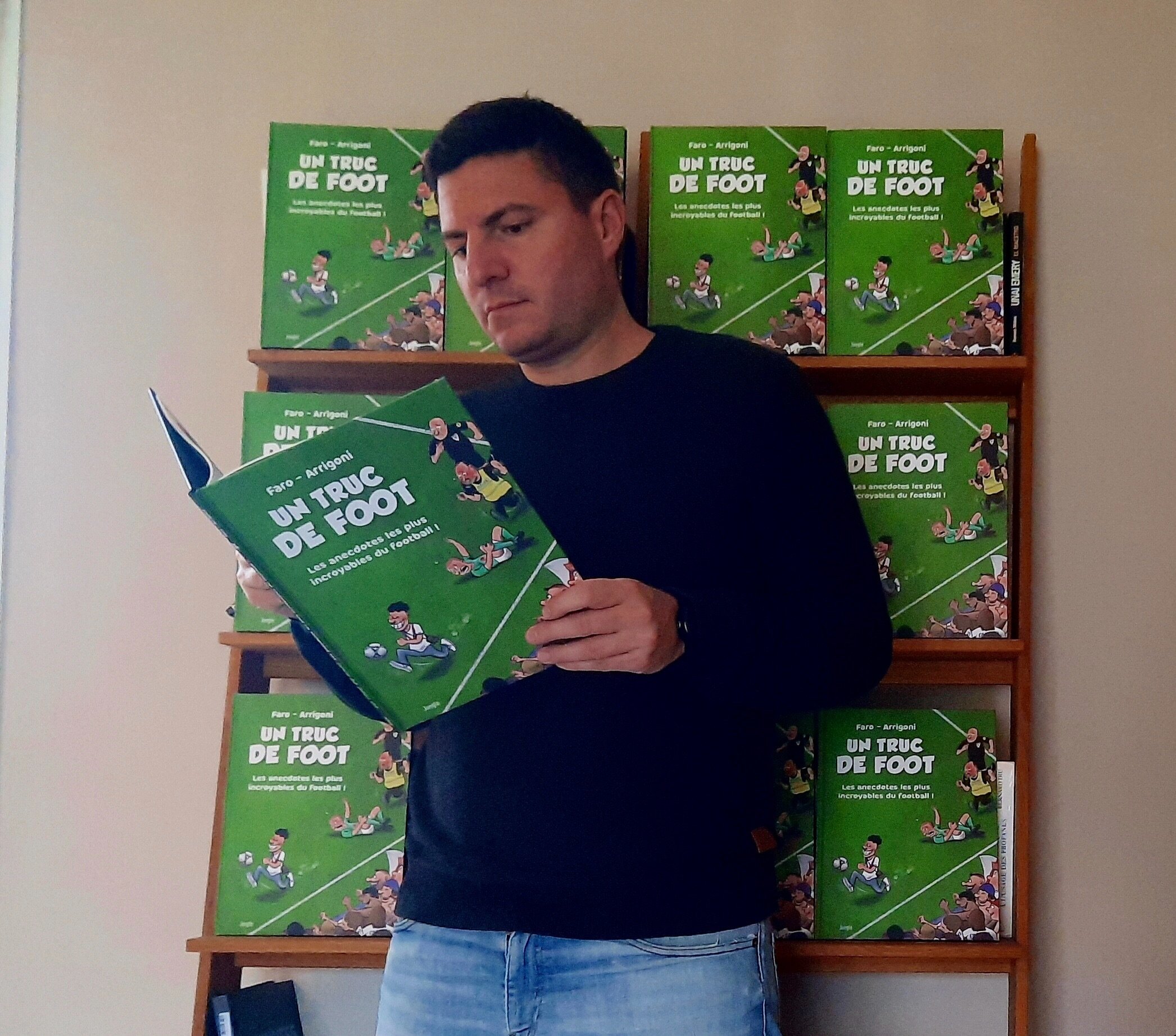 Germain Arrigoni pose avec sa BD « Un truc de foot », réalisée avec le dessinateur Faro. DR