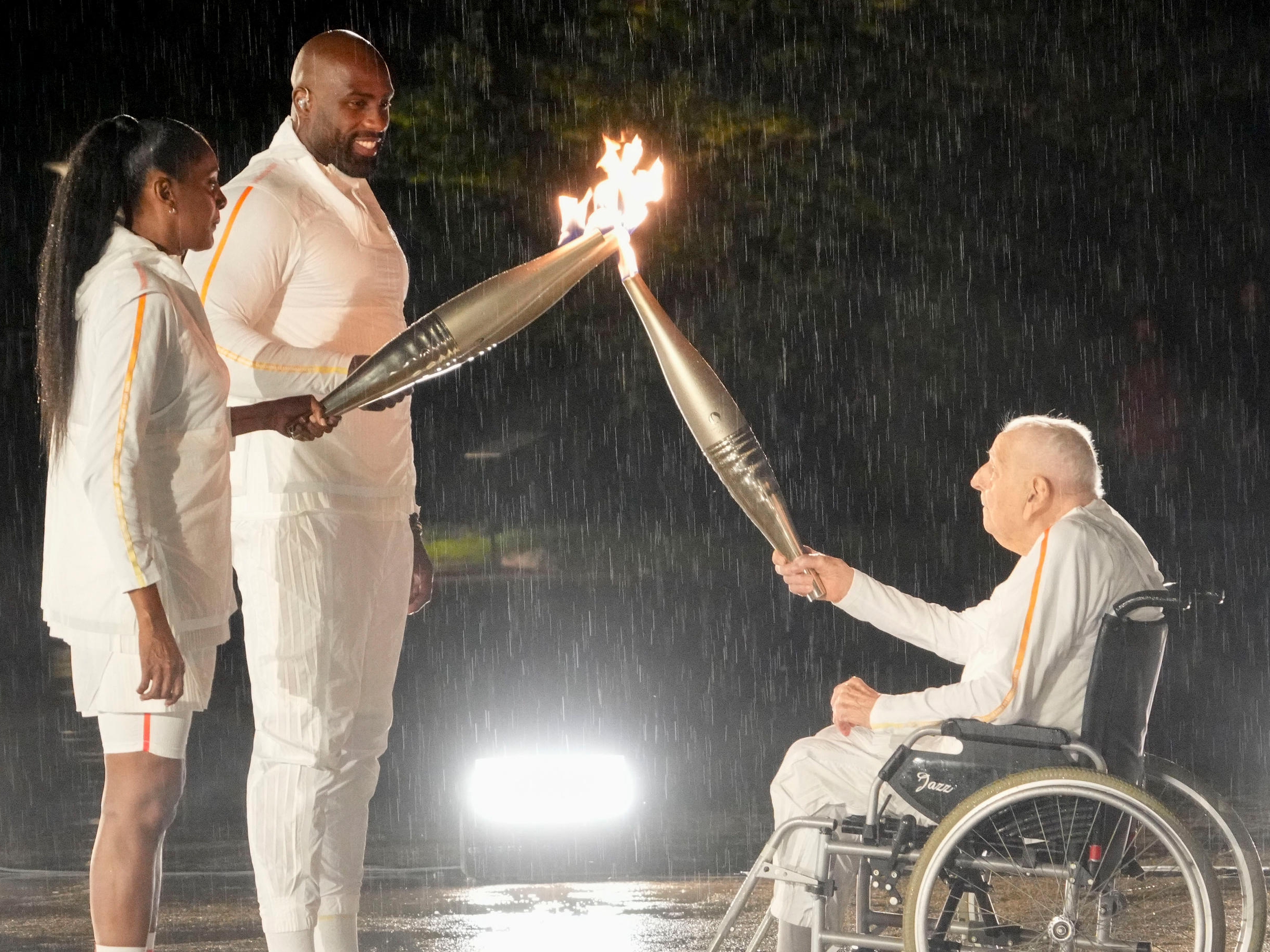 Charles Coste transmet la flamme olympique à Marie-José Pérec et Teddy Riner lors de la cérémonie d'ouverture, le 26 juillet. Icon Sport/Michael Madrid