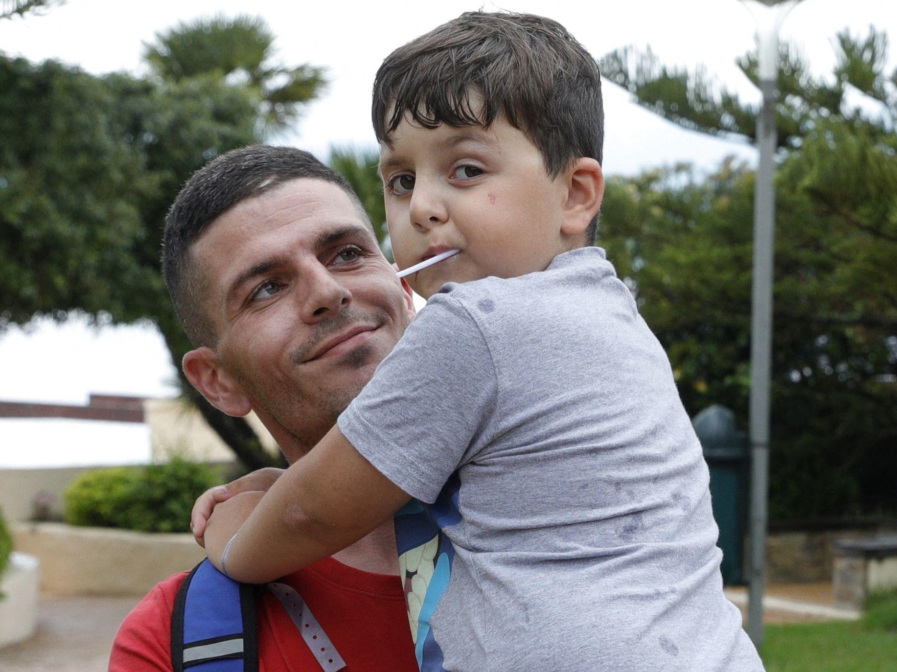 Kenzo, 8 ans, dans les bras de son papa, Laurent, au lendemain de l'agression subie à Ajaccio. AFP/Pascal Pochard-Casabianca