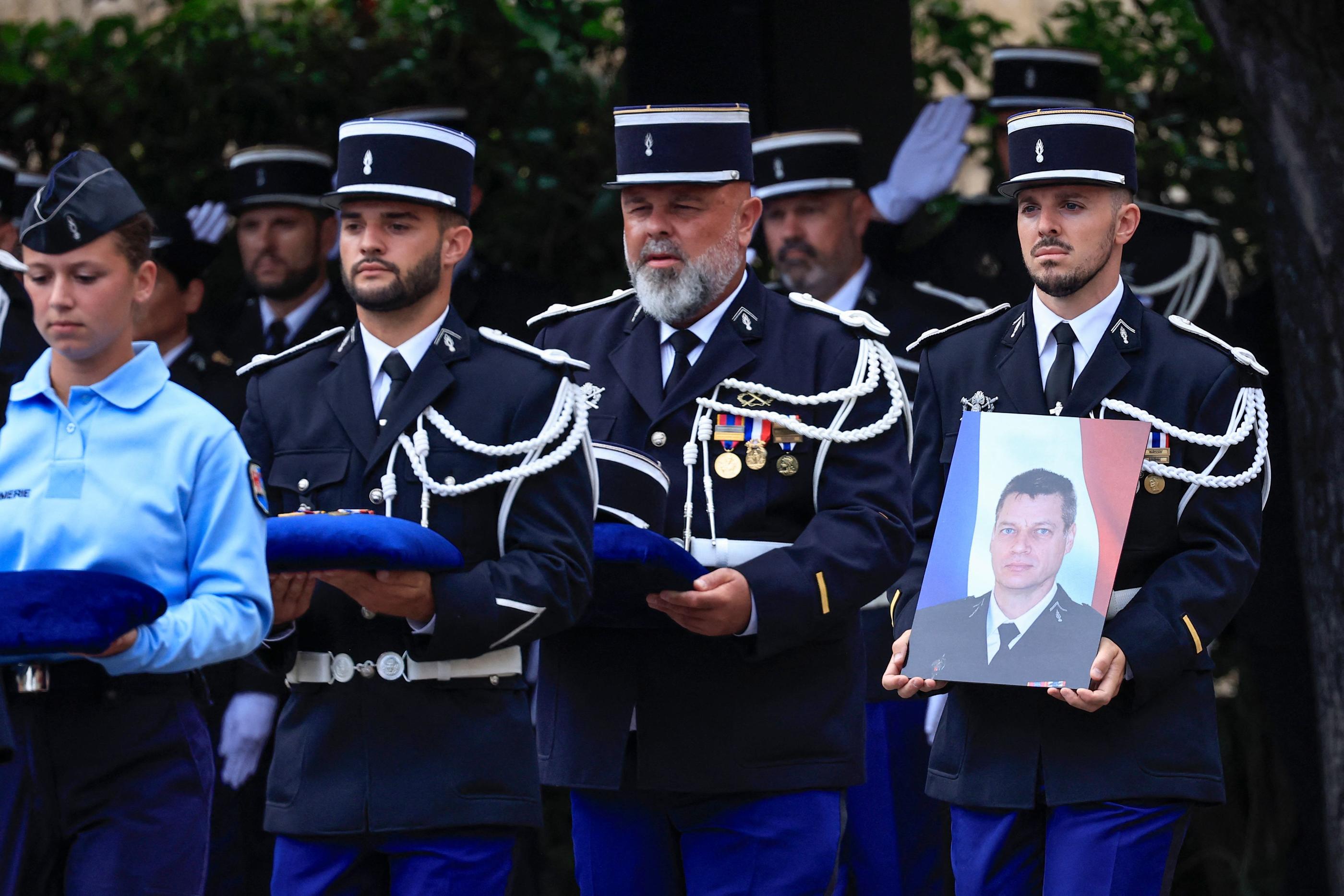 Nice, ce lundi. Un gendarme porte le portrait d'Eric Comyn, lors de l'hommage national rendu ce lundi à Nice à l'adjudant de 54 ans, mort le 28 août. AFP/Valery Hache