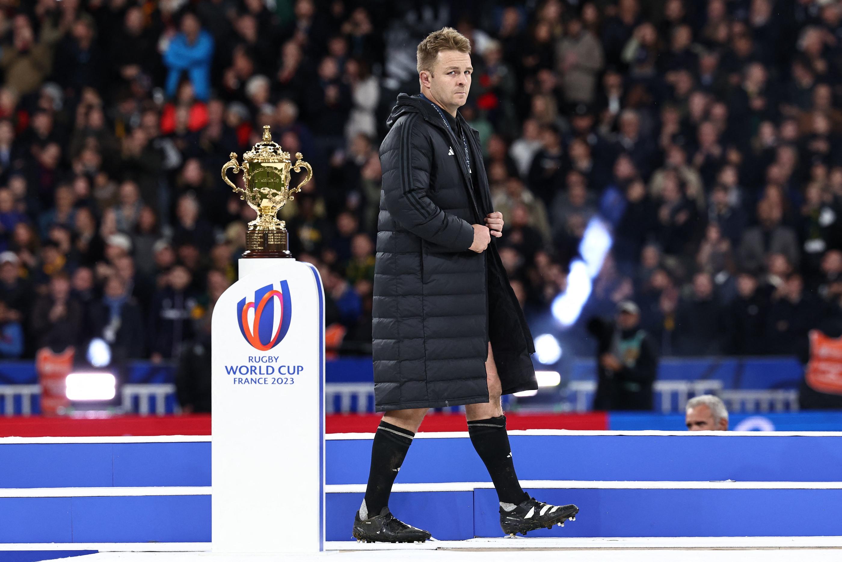 Sam Cane passe, dépité, à côté du trophée Webb-Ellis. AFP/ Anne-Christine POUJOULAT