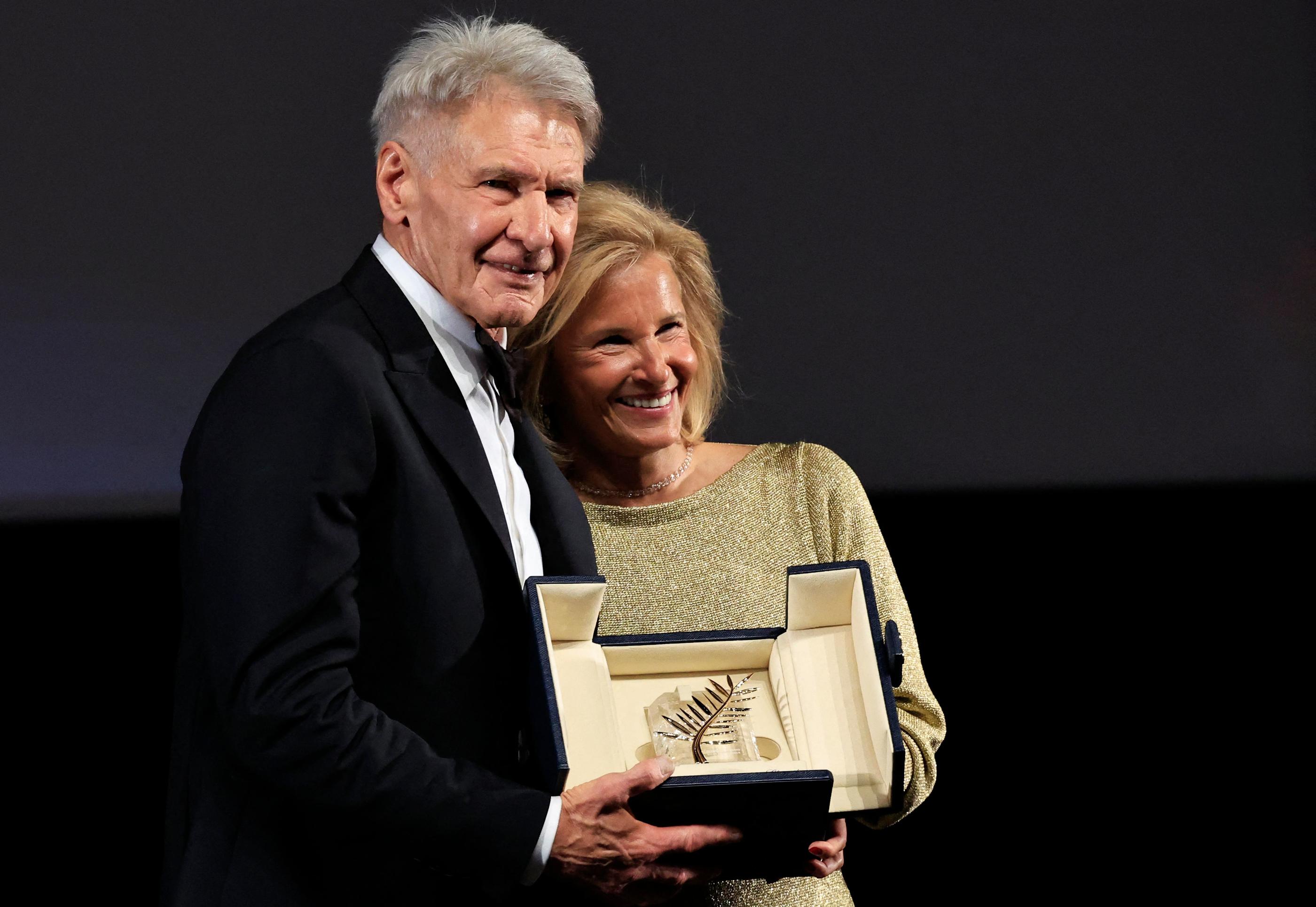 L'acteur américain Harrison Ford pose avec sa Palme d'or d'honneur, aux côtés de la présidente du Festival Iris Knobloch, à Cannes, le 18 mai 2023. AFP / Valery Hache