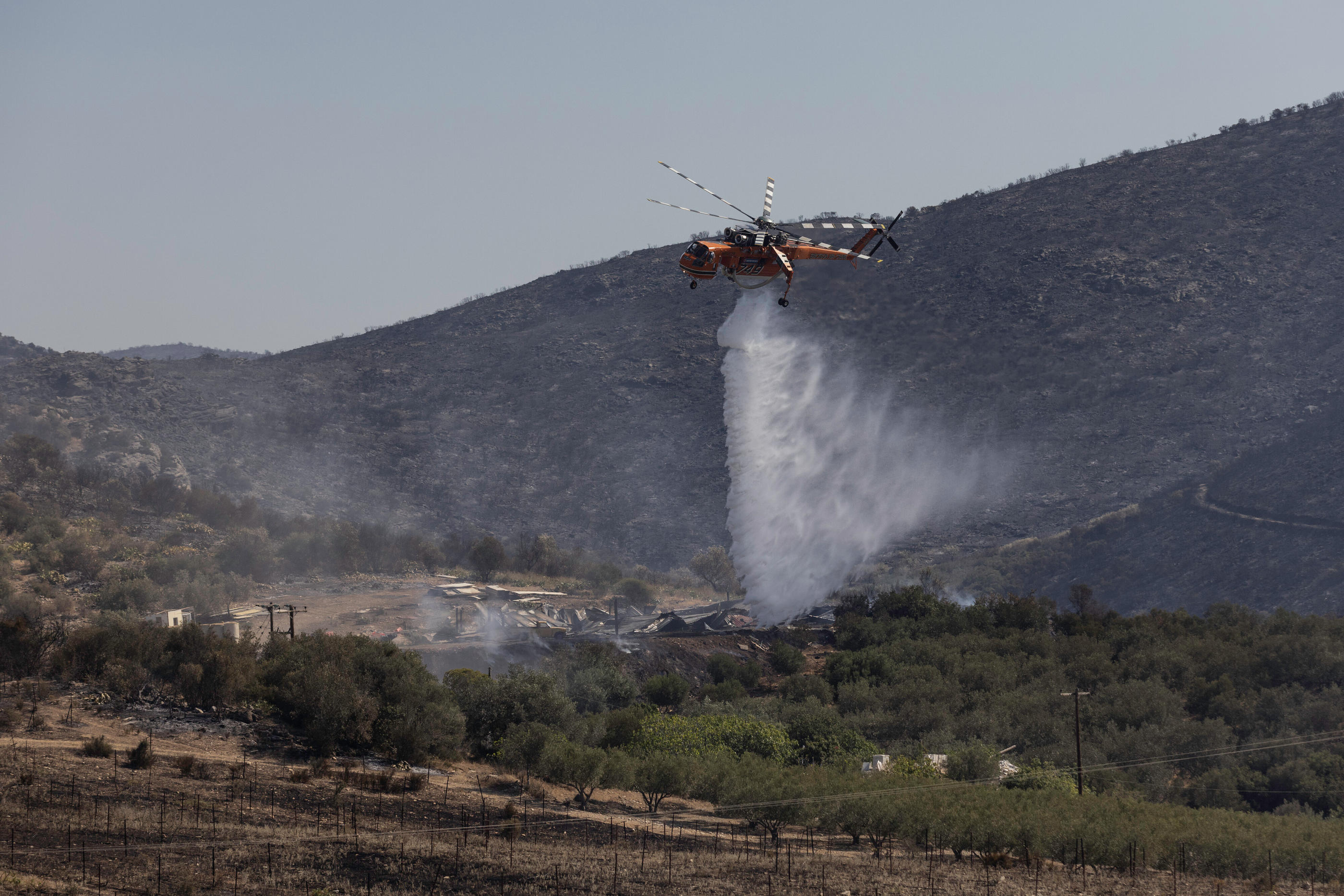 Un hélicoptère répand de l'eau sur des points fumants d'un incendie près de Nea Anchialos, en Grèce, le 28 juillet dernier. IconSport/Lefteris Partsalis