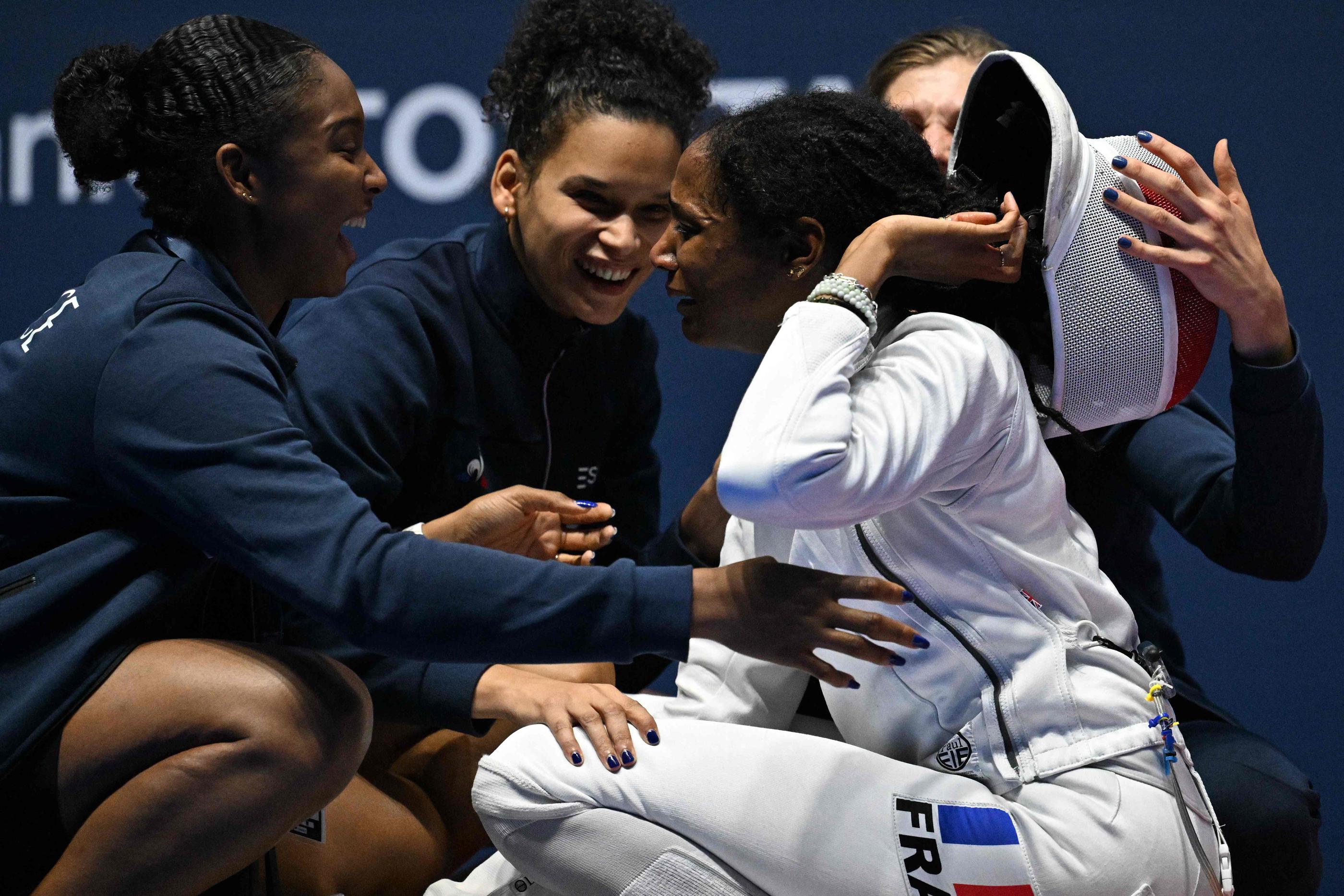 Marie-Florence Candassamy est congratulée par ses coéquipières de l'équipe de France après son sacre mondial à Milan. AFP/Andreas SOLARO