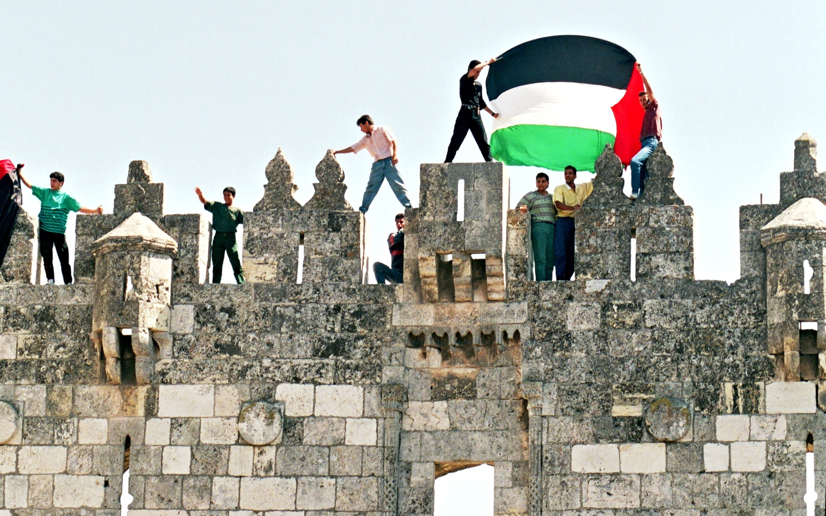 Les Palestiniens agitent leur drapeau le 11 septembre 1993 sur le mur de la vieille ville de Jérusalem pour célébrer les accords d’Oslo du 10 septembre. AFP/Menahem Kahana