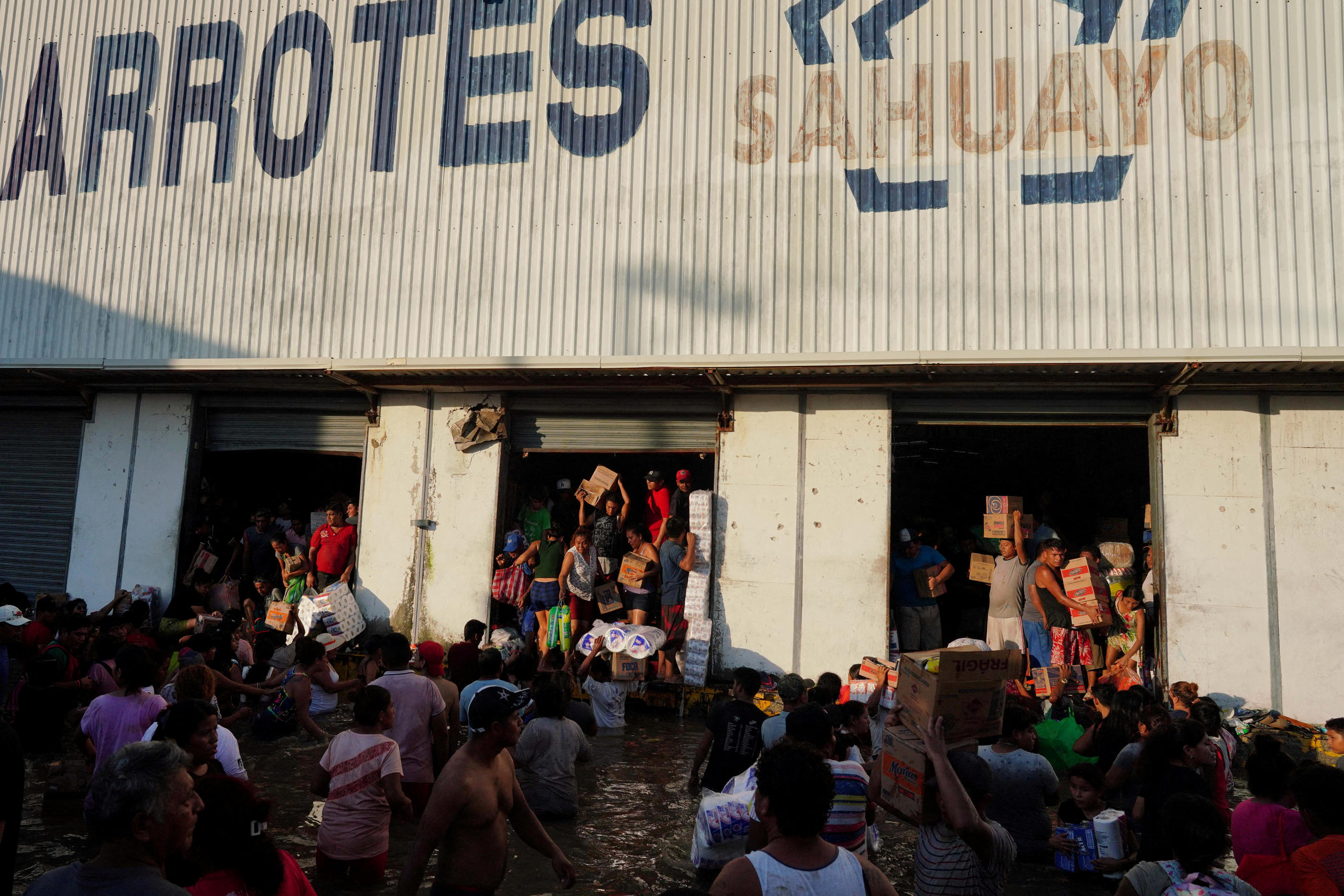 Des habitants d'Acapulco dévastée pillent, jeudi, les stocks d'un supermarché de la ville, éventré par l'ouragan Otis. REUTERS/Alexandre Meneghini