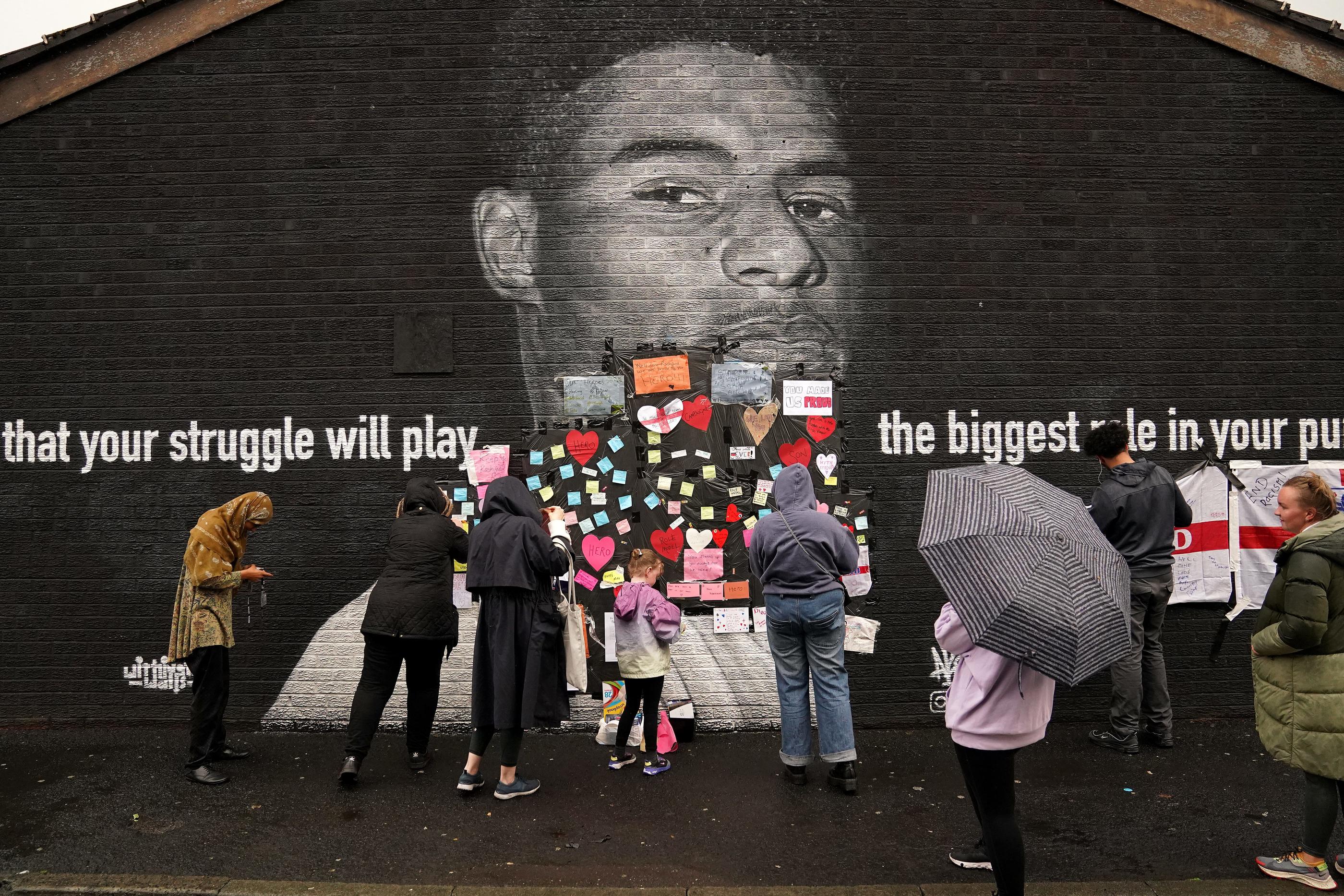 Des supporters collent des messages et des coeurs sur la fresque de Marcus Rashford vandalisée à Manchester.