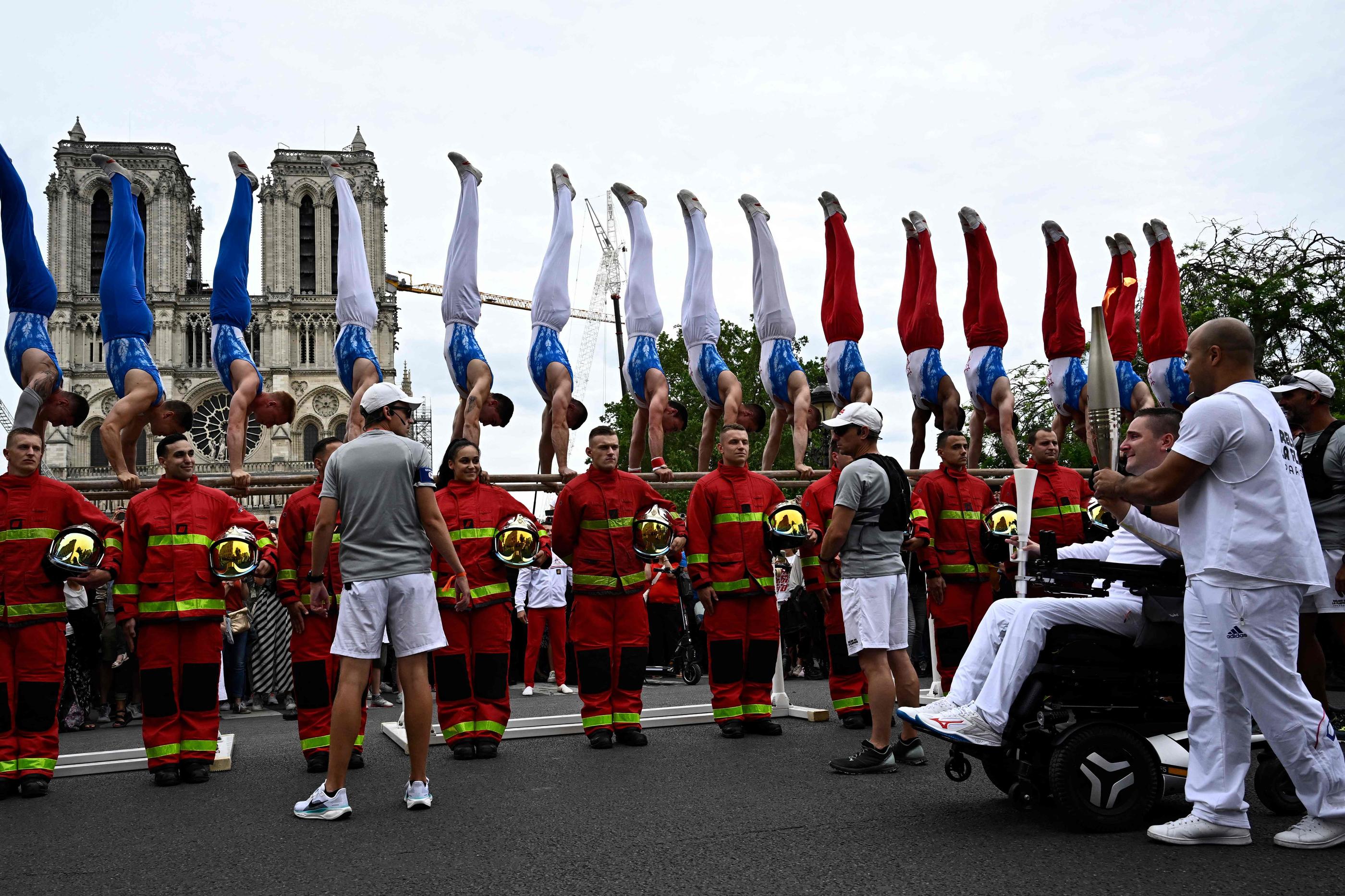 Parvis de Notre-Dame, Paris (IVe), ce dimanche 14 juillet. Timothée Bernardeau a porté la flamme sous une haie d’honneur des pompiers devant la cathédrale. AFP/Julien de Rosa