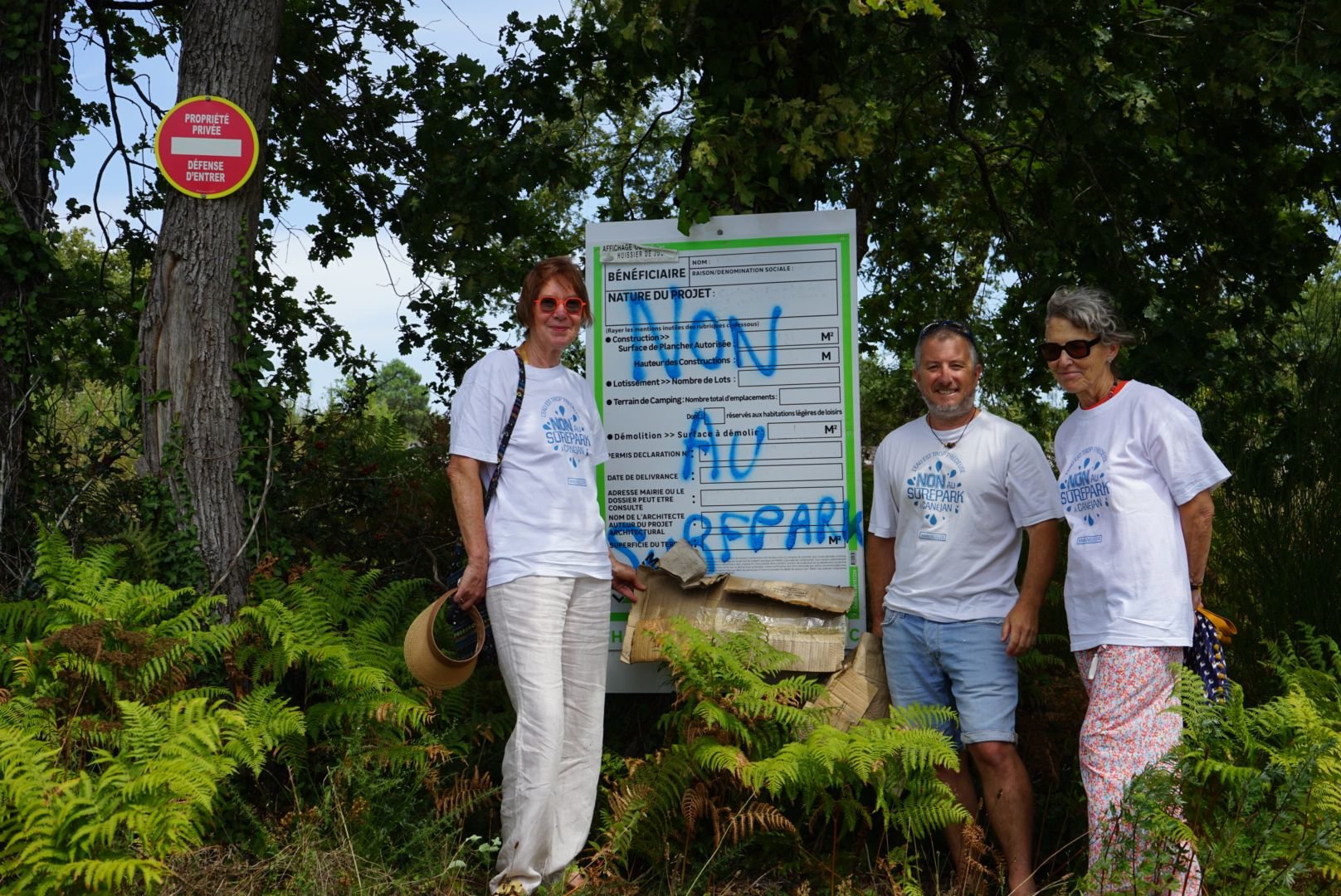 Martine, Guillaume et Brigitte du collectif « Non au surf en boîte » devant le permis de construire accordé par la mairie de Canéjan : ils ne sont pas à l'initiative du tag sur le panneau : « Nous, on est dans la légalité », précisent-ils. LP/Klervi Le Cozic