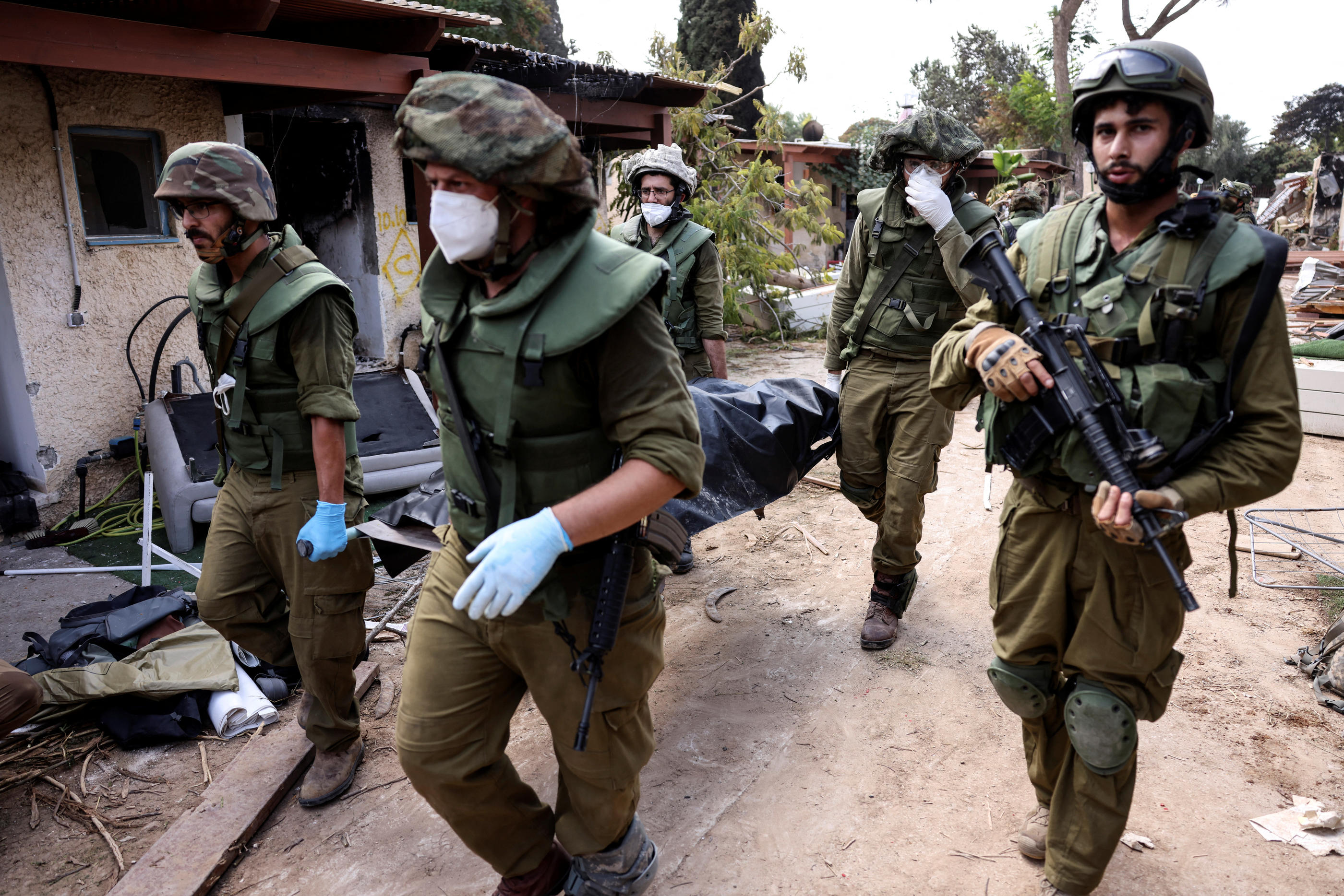 Des soldats israéliens transportent un cadavre dans le kibboutz Kfar Aza, le 10 octobre 2023. REUTERS/Ronen Zvulun