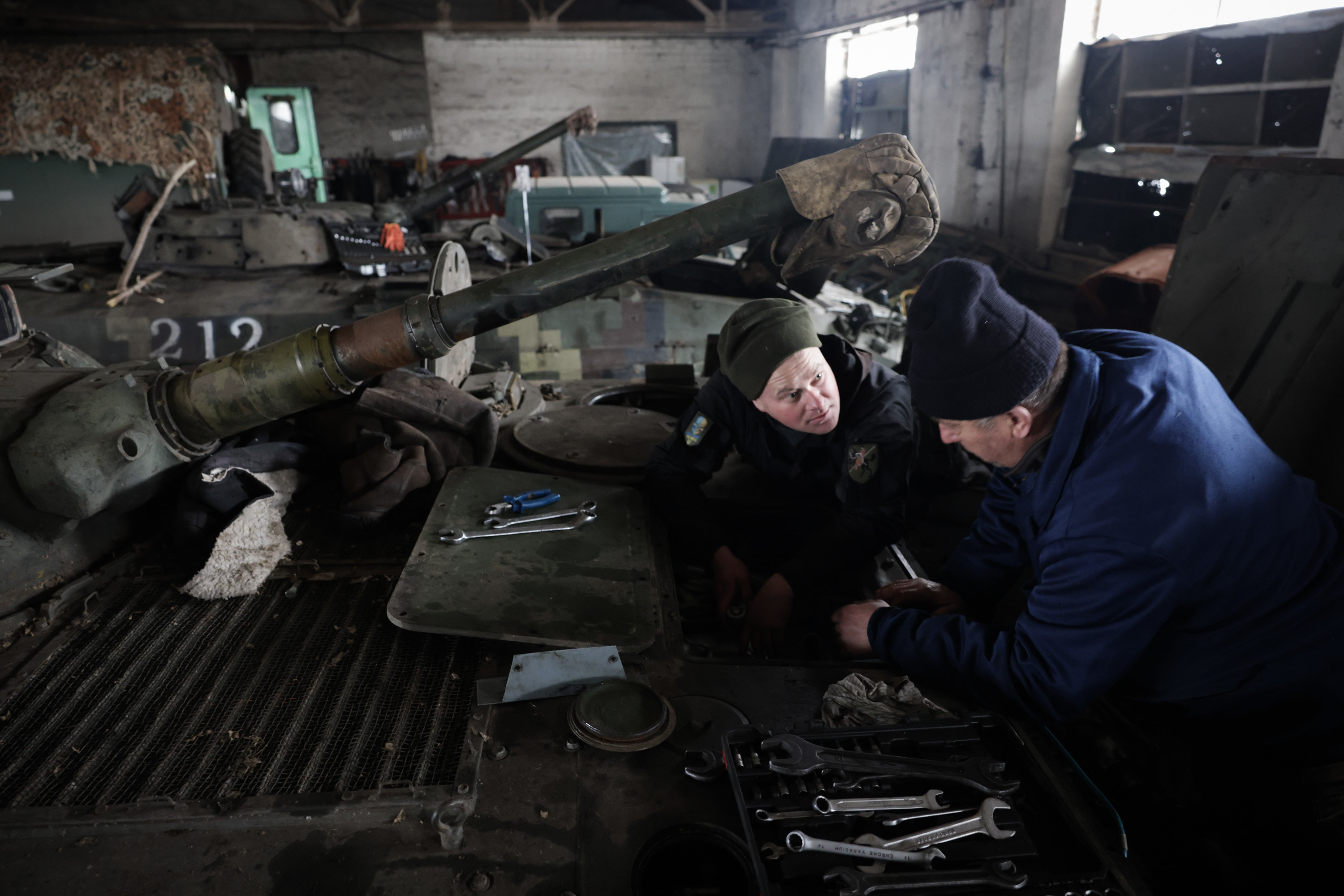 Myrnograd (Ukraine), le 17 février 2023. Les mécaniciens jouent de la clé à molette à deux mètres de hauteur, les pieds dans le moteur d’un blindé de 300 chevaux. LP/Philippe de Poulpiquet