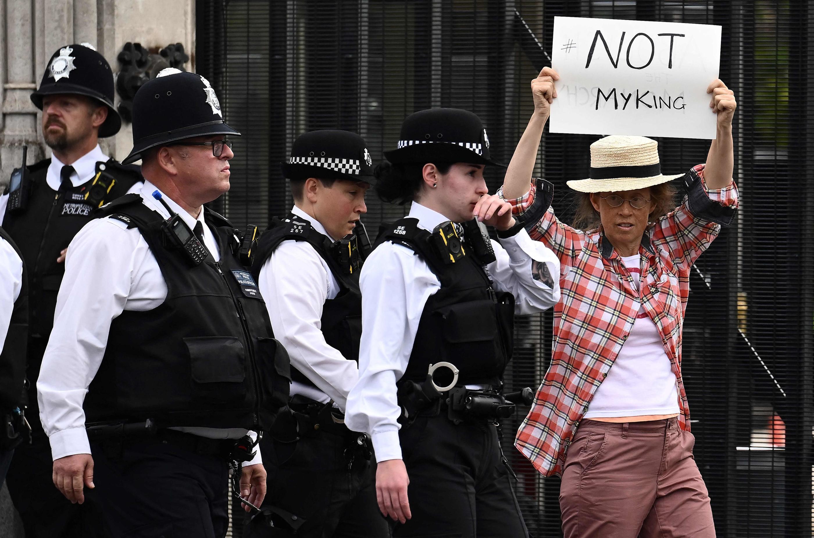 Une manifestante, brandissant une pancarte portant l'inscription "Pas mon roi", a été arrêtée devant le Parlement britannique ce lundi. AFP/Marco Bertorello