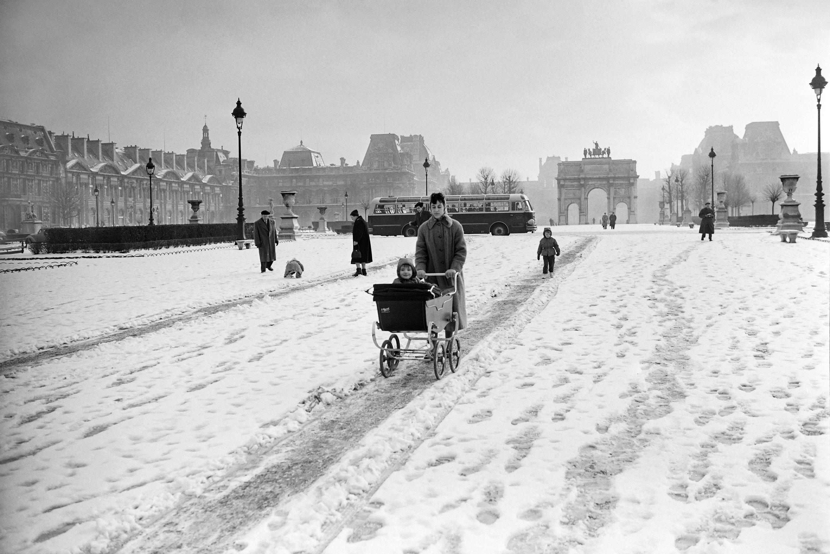 Une femme pousse un landau sur le sol enneigé du jardin des Tuileries, à Paris, le 13 février 1956. AFP