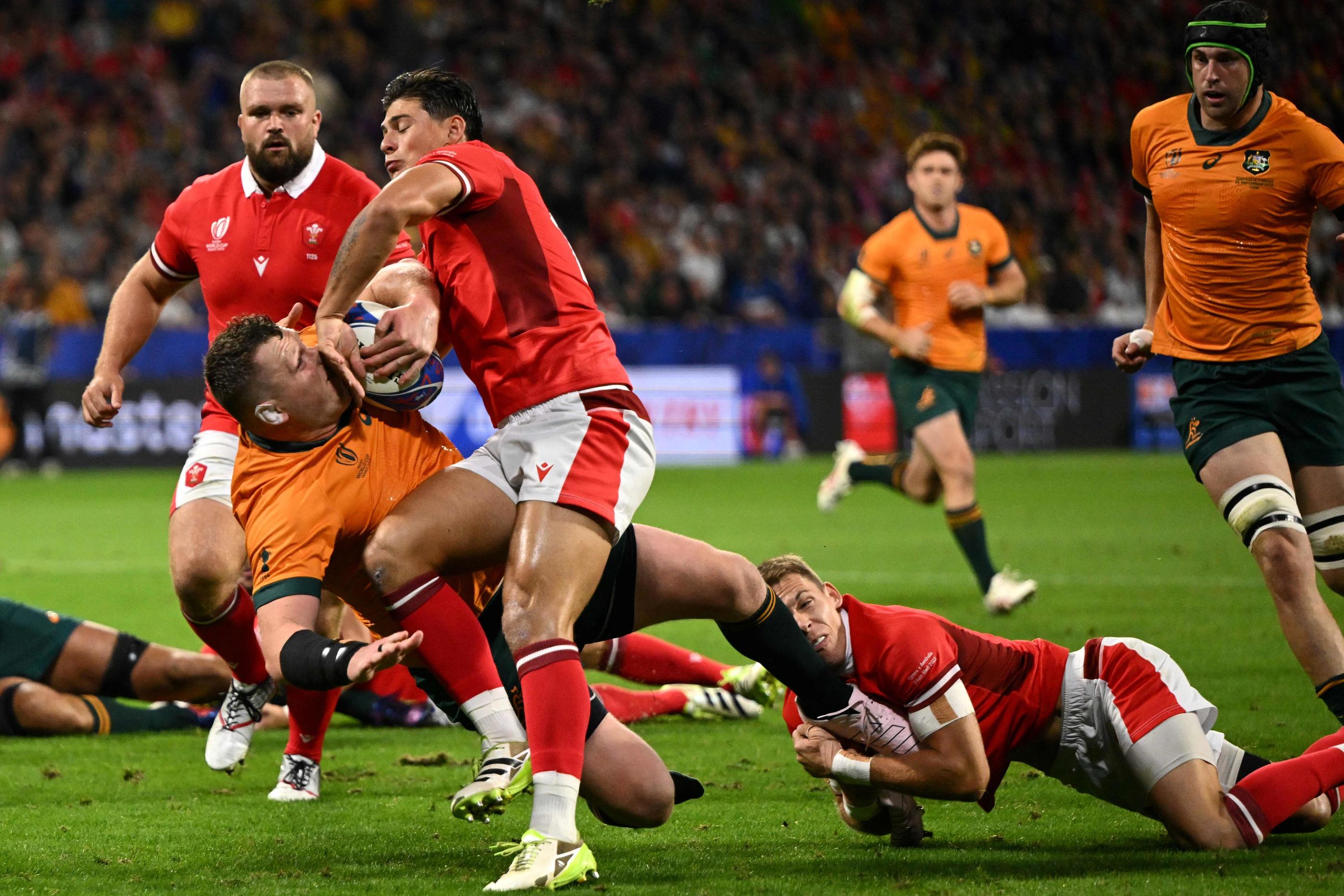 Louis Rees-Zammit résiste au pilier australien Angus Bell, symbole de la domination gallois lors de ce match. (Photo by SEBASTIEN BOZON / AFP)