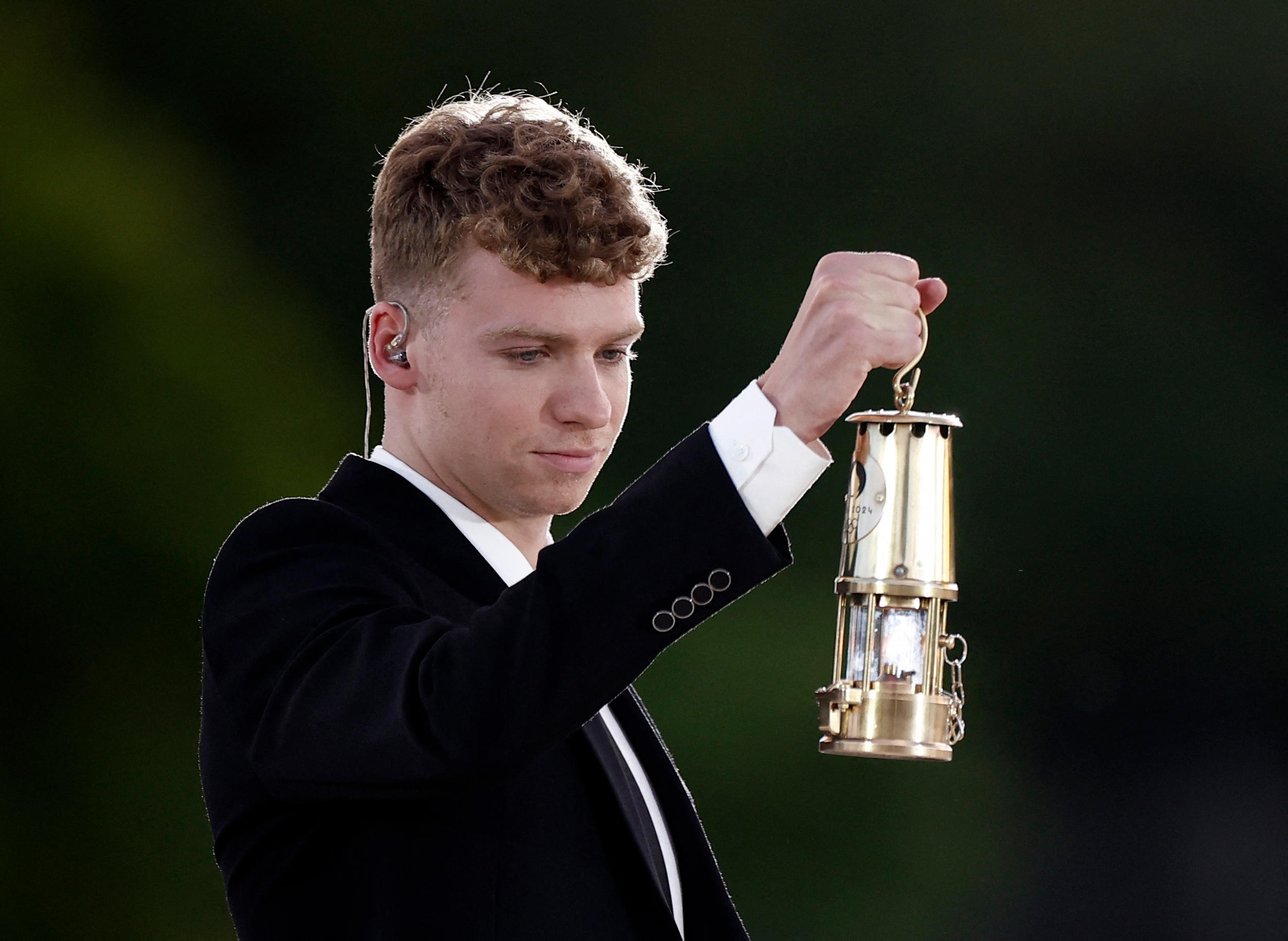 Léon Marchand s’est emparé de la lanterne de la « vraie » flamme, exposée depuis deux semaines dans le jardin des Tuileries, à côté de la vasque. LP/Fred Dugit REUTERS/Benoit Tessier