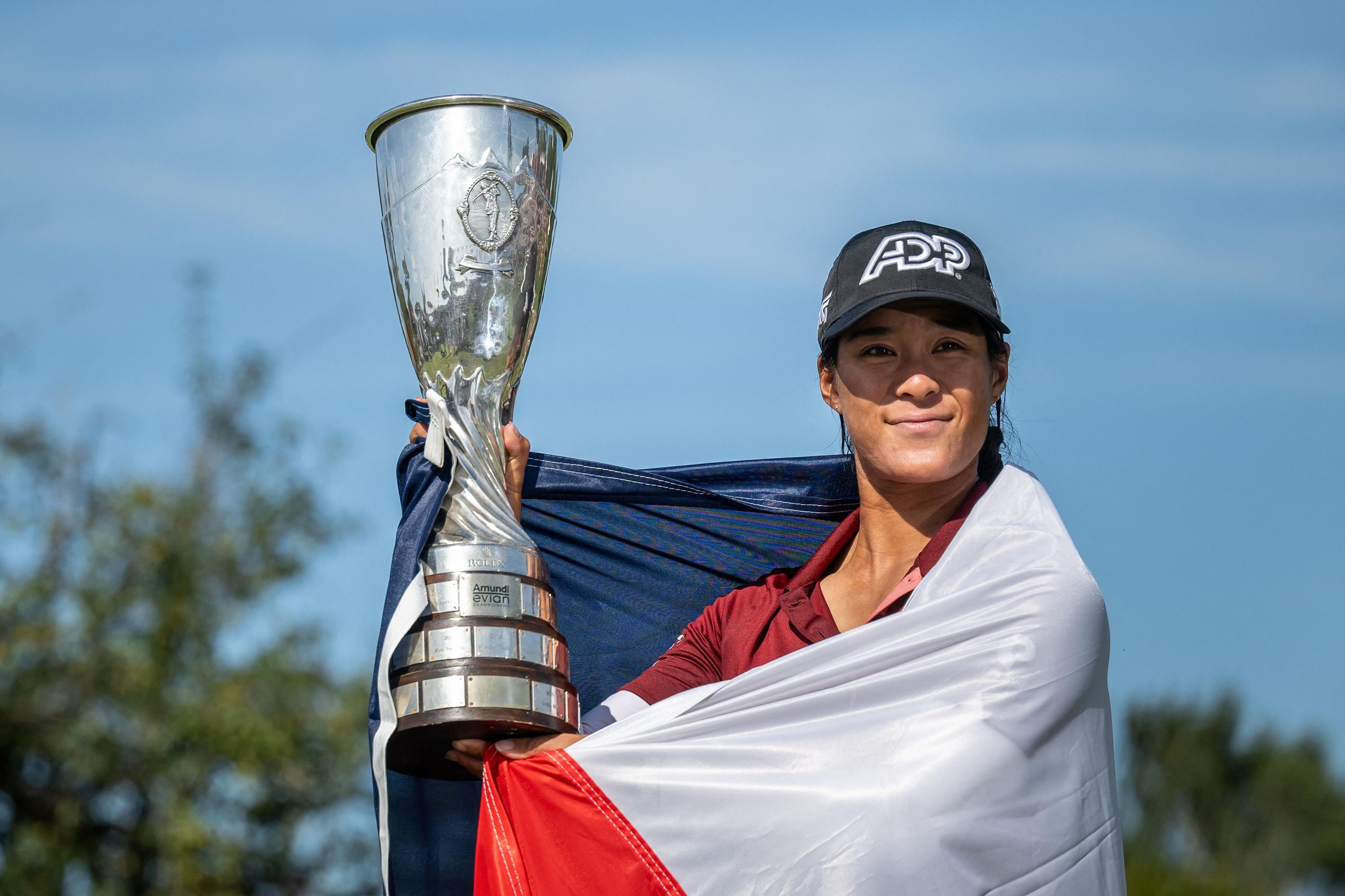 TOPSHOT - France's Celine Boutier, wrapped in a French flag, poses with her trophy after winning the Evian Championship, a women's LPGA major golf tournament in Evian-les-Bains, French Alps, on July 30, 2023. (Photo by Fabrice COFFRINI / AFP)
