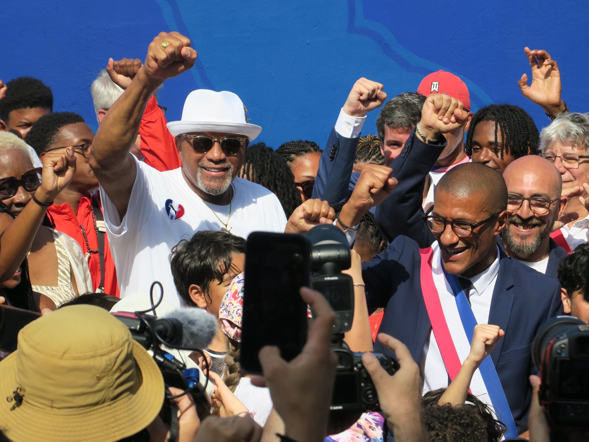 Saint-Ouen (Seine-Saint-Denis), ce mardi 30 juillet. Vingt ans après l'ouverture d'un gymnase portant son nom, Tommie Smith (avec le chapeau blanc) est revenu de nouveaux terrains et un podium, réplique de celui sur lequel il a levé son point ganté à Mexico en 1968. LP/A.L.