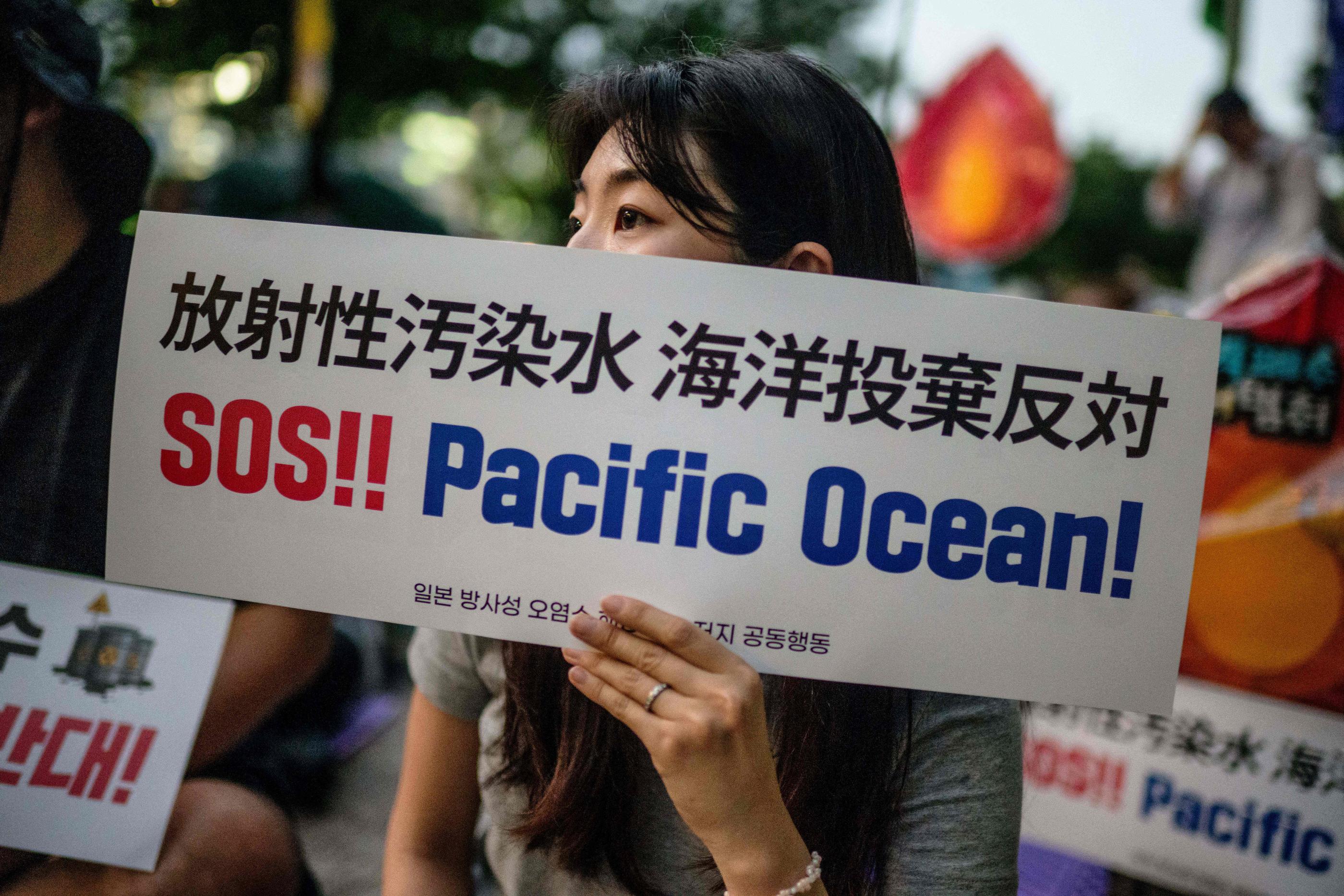 Avec sa pancarte sur laquelle on peut lire SOS !! Océan Pacifique !, une manifestante proteste à Séoul contre le rejet prévu des eaux usées de la centrale nucléaire dans le Pacifique. AFP/Anthony Wallace