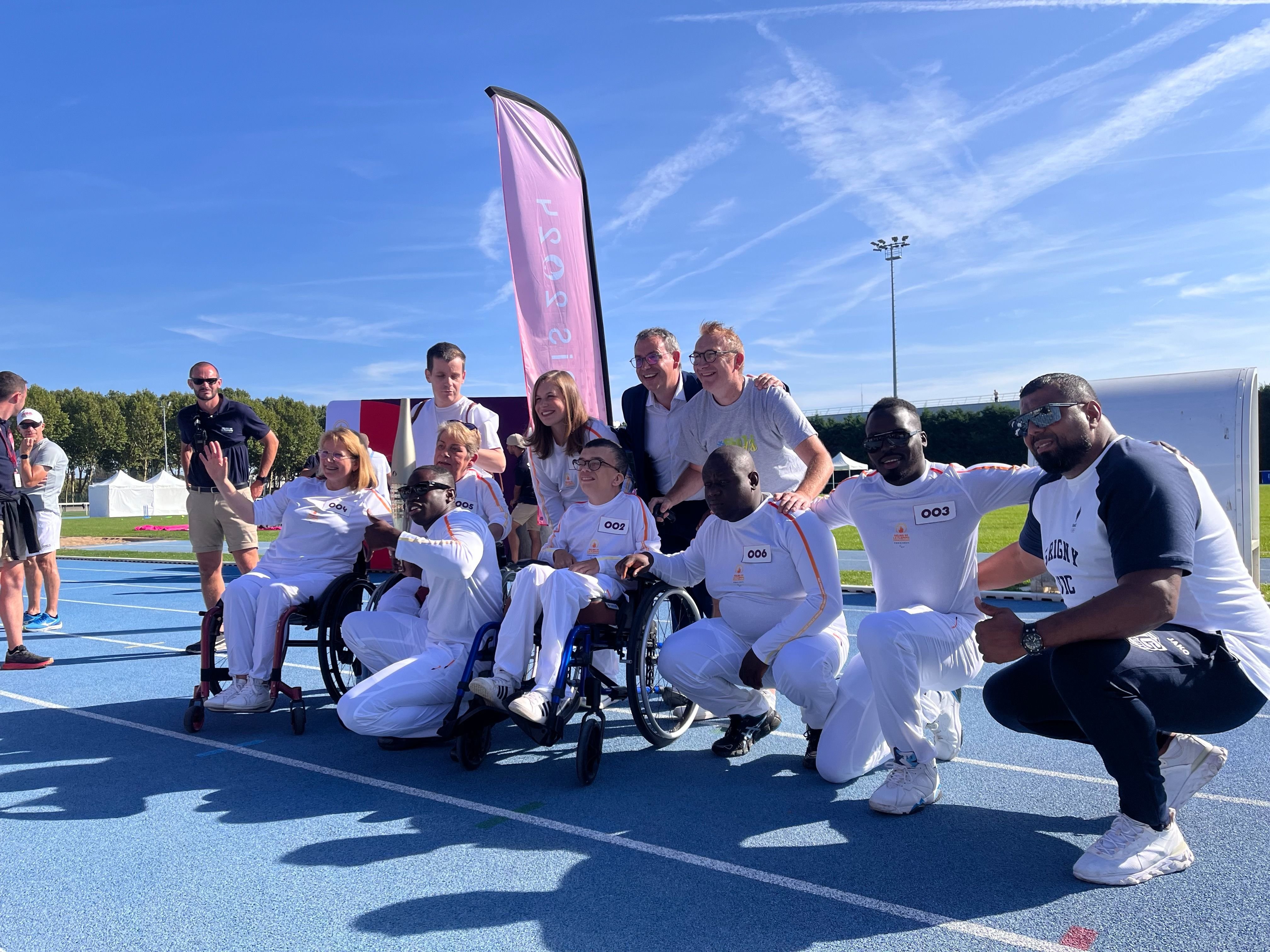 Grigny (Essonne), mardi 27 août 2024. Sept relayeurs, dont le duo d'influenceurs de la Grande-Borne Golo (deuxième à gauche, pouce levé) et Ritchie (numéro 006) ont porté la flamme paralympique au stade Jean-Miaud. LP/Nolwenn Cosson