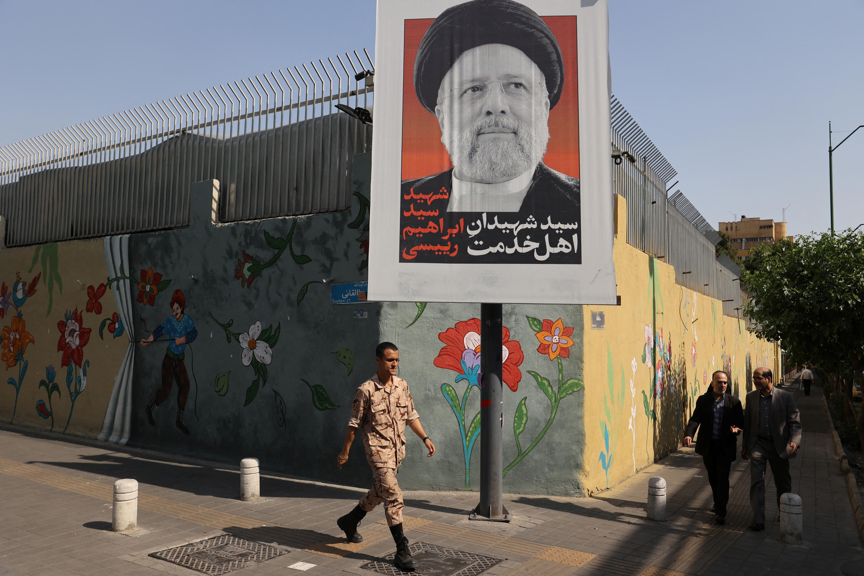 Un passant marche devant une image du président défunt Ebrahim Raïssi à Téhéran, le 10 mai. REUTERS/Majid Asgaripour/WANA