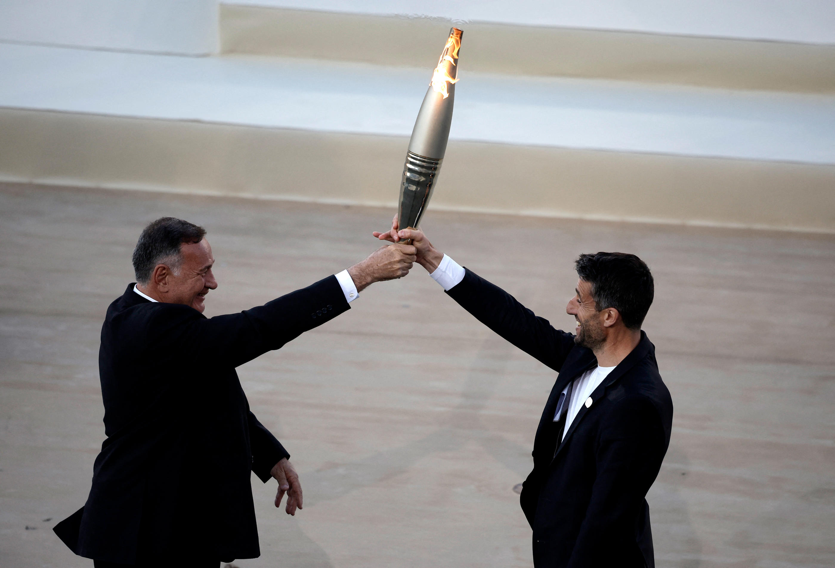 Le président du comité olympique grec Spyros Capralos transmet la flamme au patron du Cojo Tony Estanguet. REUTERS/Louisa Gouliamaki