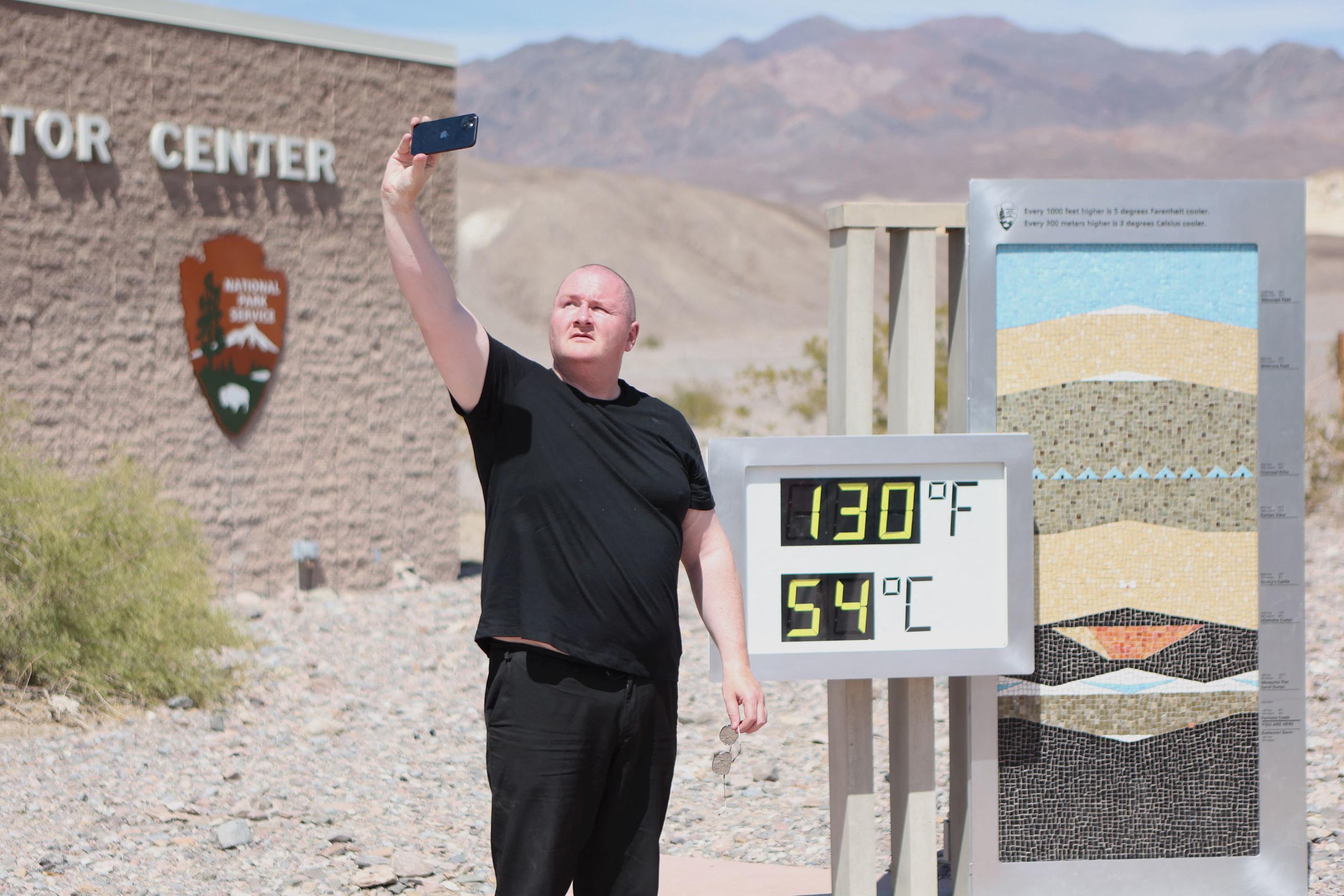 Un touriste britannique prend un selfie à côté d'un panneau affichant la température enregistré dans la Vallée de la Mort (Californie), le 16 juillet 2023 lors d'une vague de chaleur. AFP/Ronda Churchill