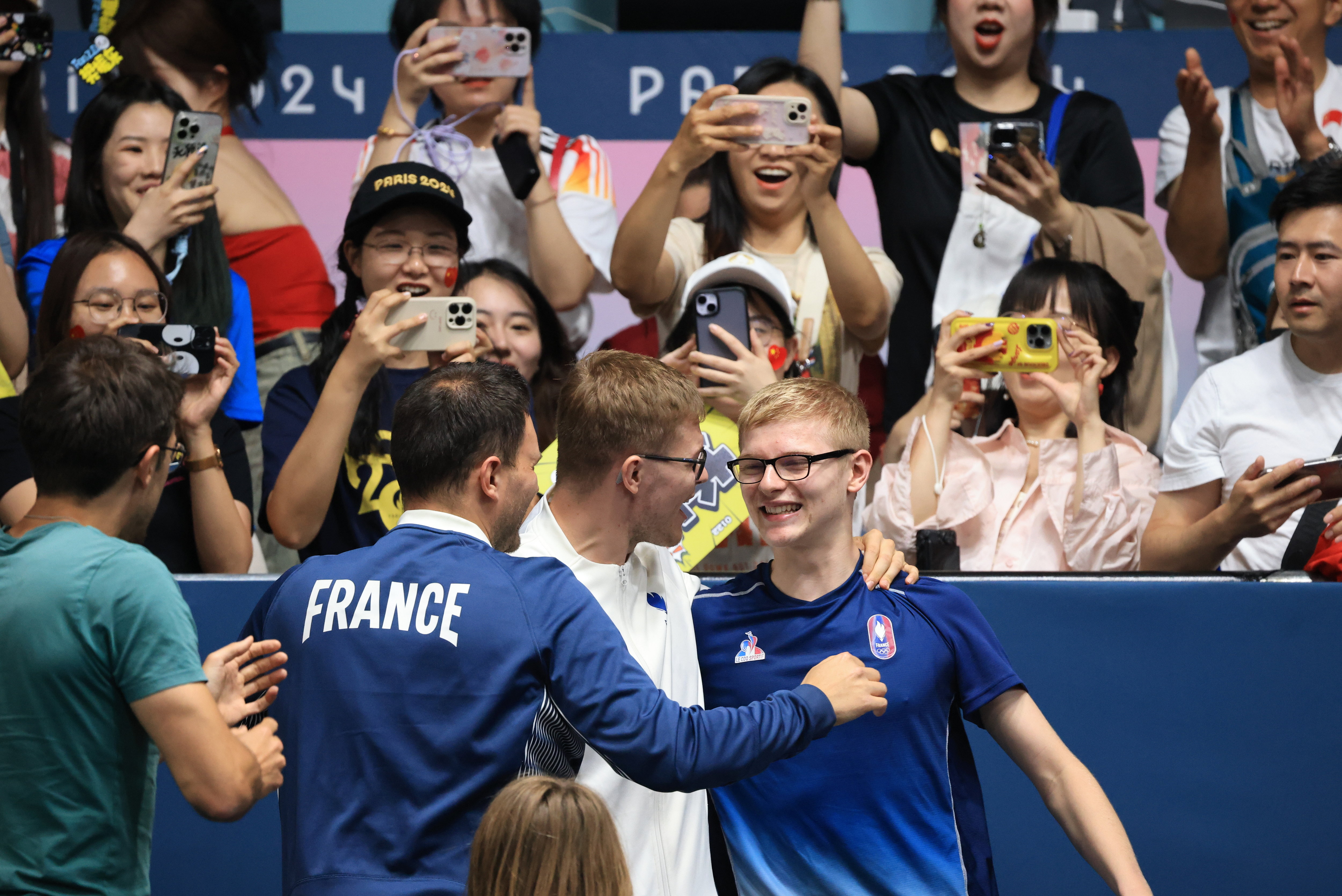 Médaillé de bronze à seulement 17 ans, le pongiste Félix Lebrun savoure sa victoire face au Brésilien Calderano avec son frère Alexis (au centre) et son entraîneur Nathanaël Molin. LP / Olivier Arandel