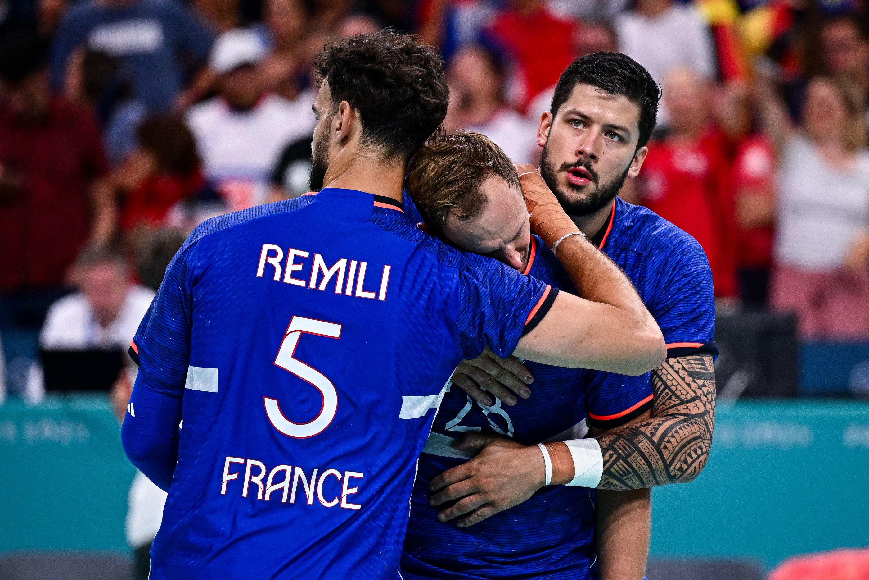 Nedim Remili et Nicolas Tournat consolent Valentin Porte, qui jouait son dernier match avec l'équipe de France de handball, après la défaite face à l'Allemagne en quart de finale des JO. Baptiste Fernandez/Icon Sport