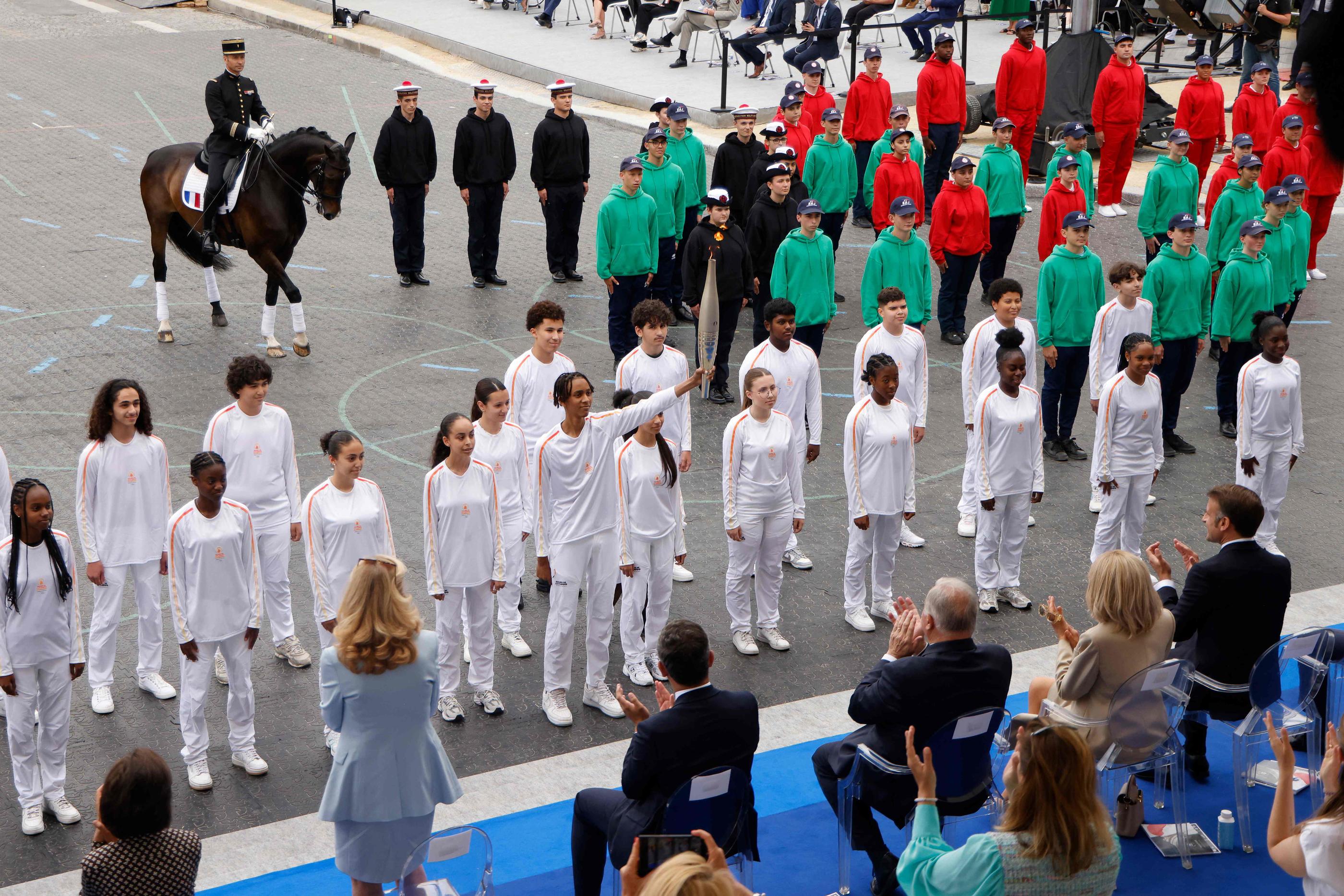 Paris, ce 14 juillet. Les collégiens de Seine-Saint-Denis se sont passé la flamme olympique de main en main, sous les applaudissements des officiels, dont le couple présidentiel. AFP/Ludovic Marin