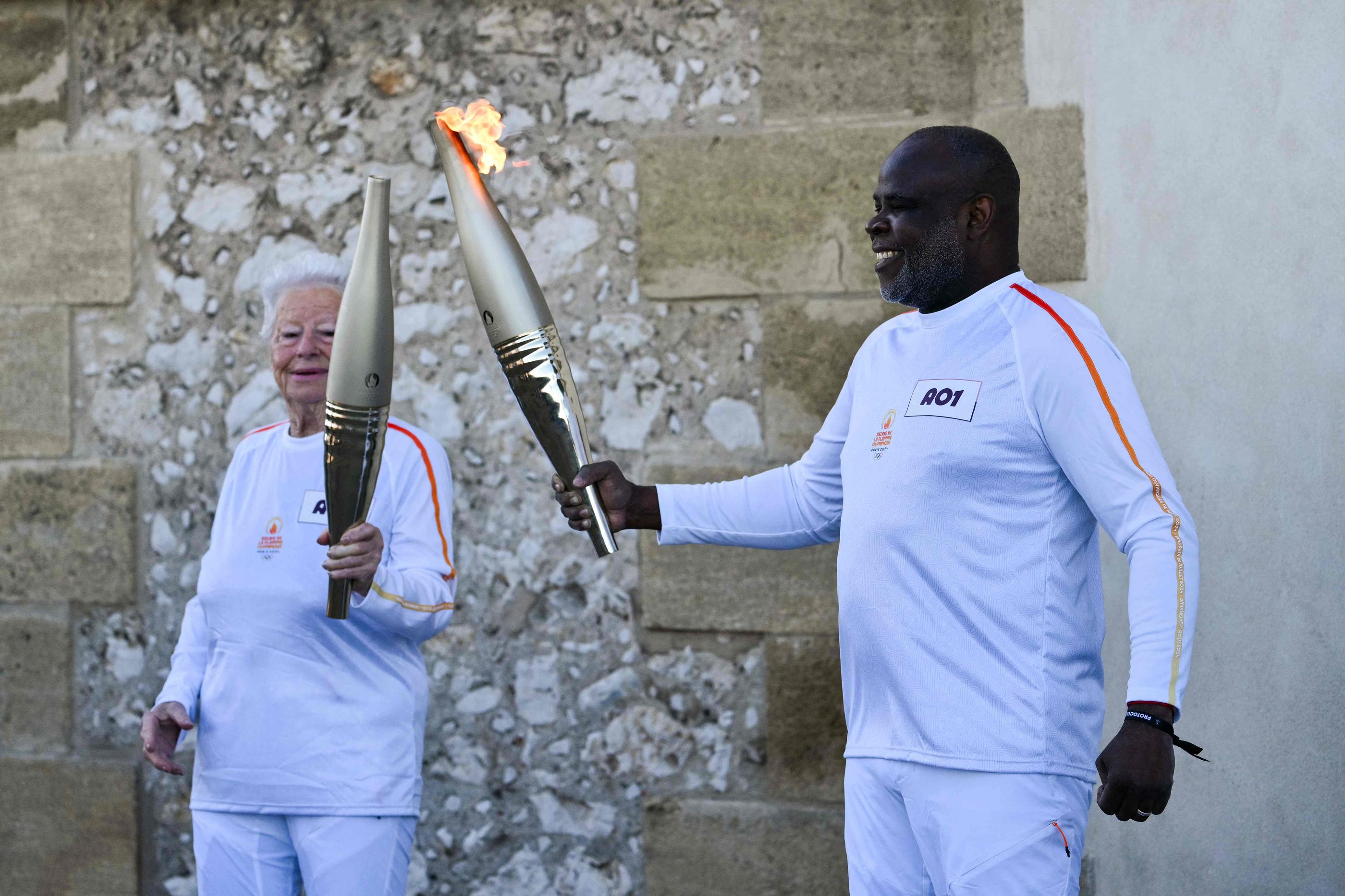 Basile Boli, légende du football marseillais, a été le premier à porter la torche qui arrivera à Paris pour les JO le 26 juillet. AFP/Christophe Simon