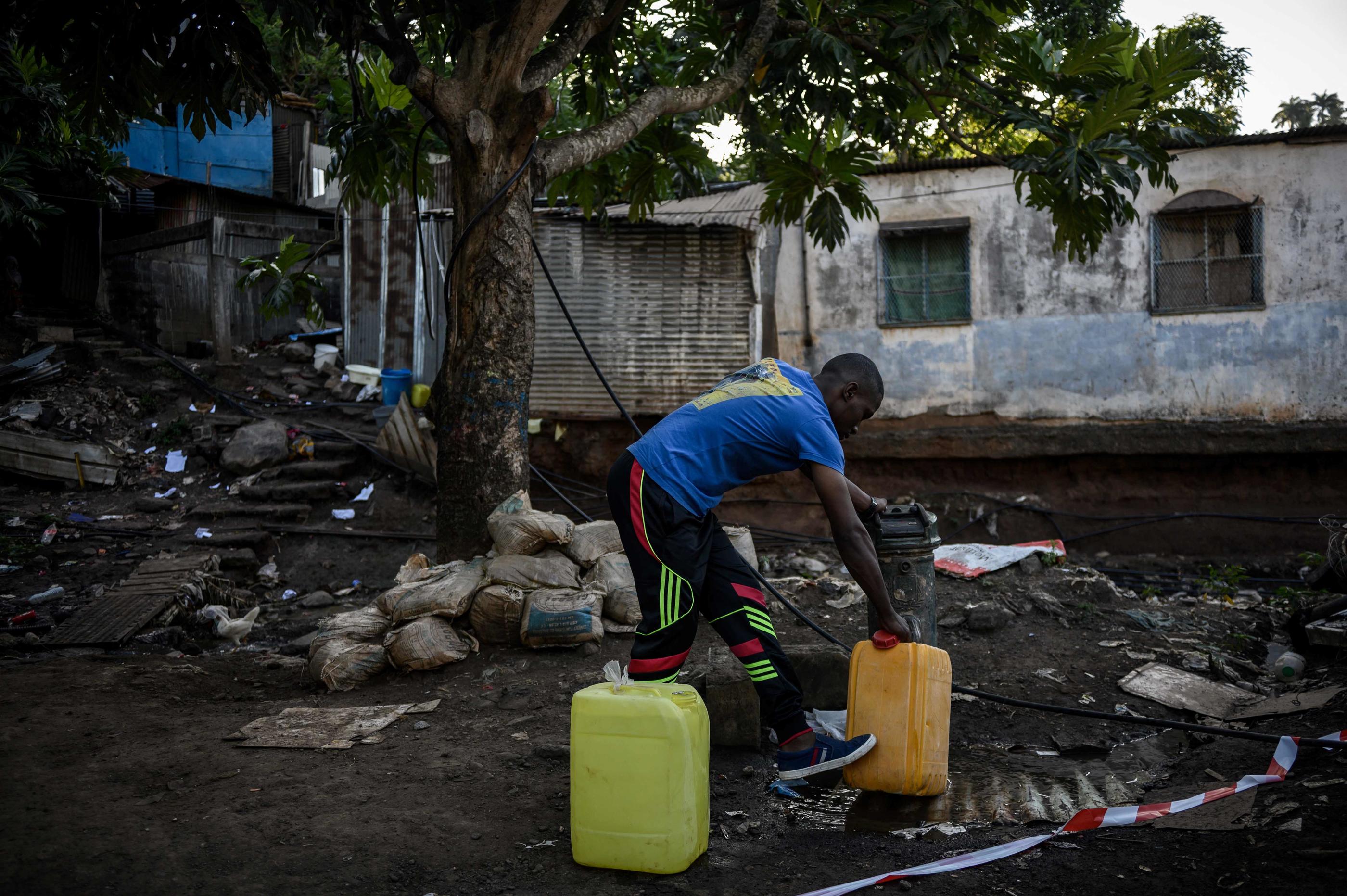 Un habitant de Koungou (Mayotte) remplit des bidons d'eau potable près du bidonville « Talus 2 », le 23 mai 2023. AFP/Philippe Lopez