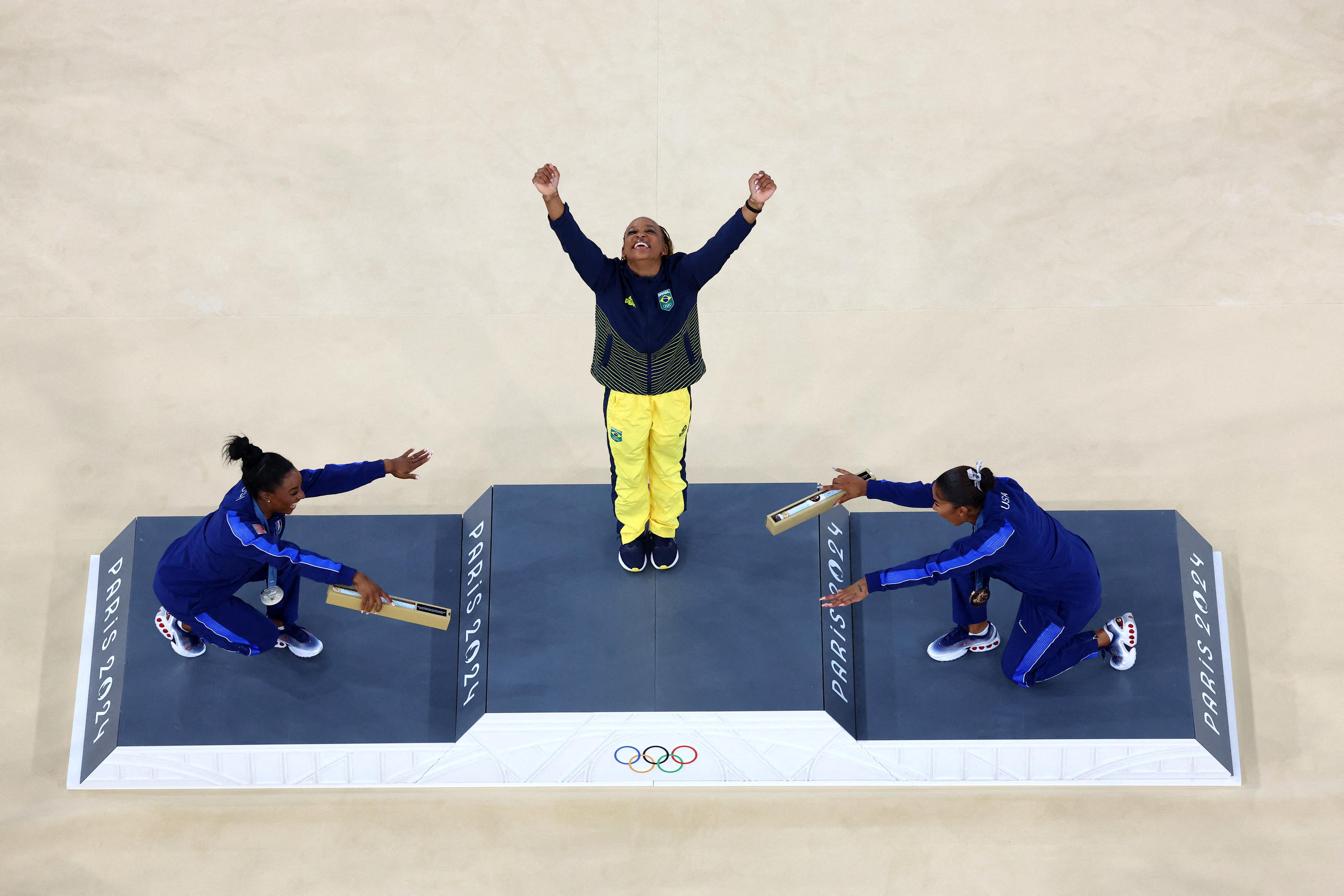 Simone Biles (à gauche) et Jordan Chiles se sont toutes deux agenouillées au moment où Rebeca Andrade montait sur la première marche du podium pour recevoir sa médaille d'or. REUTERS/Athit Perawongmetha