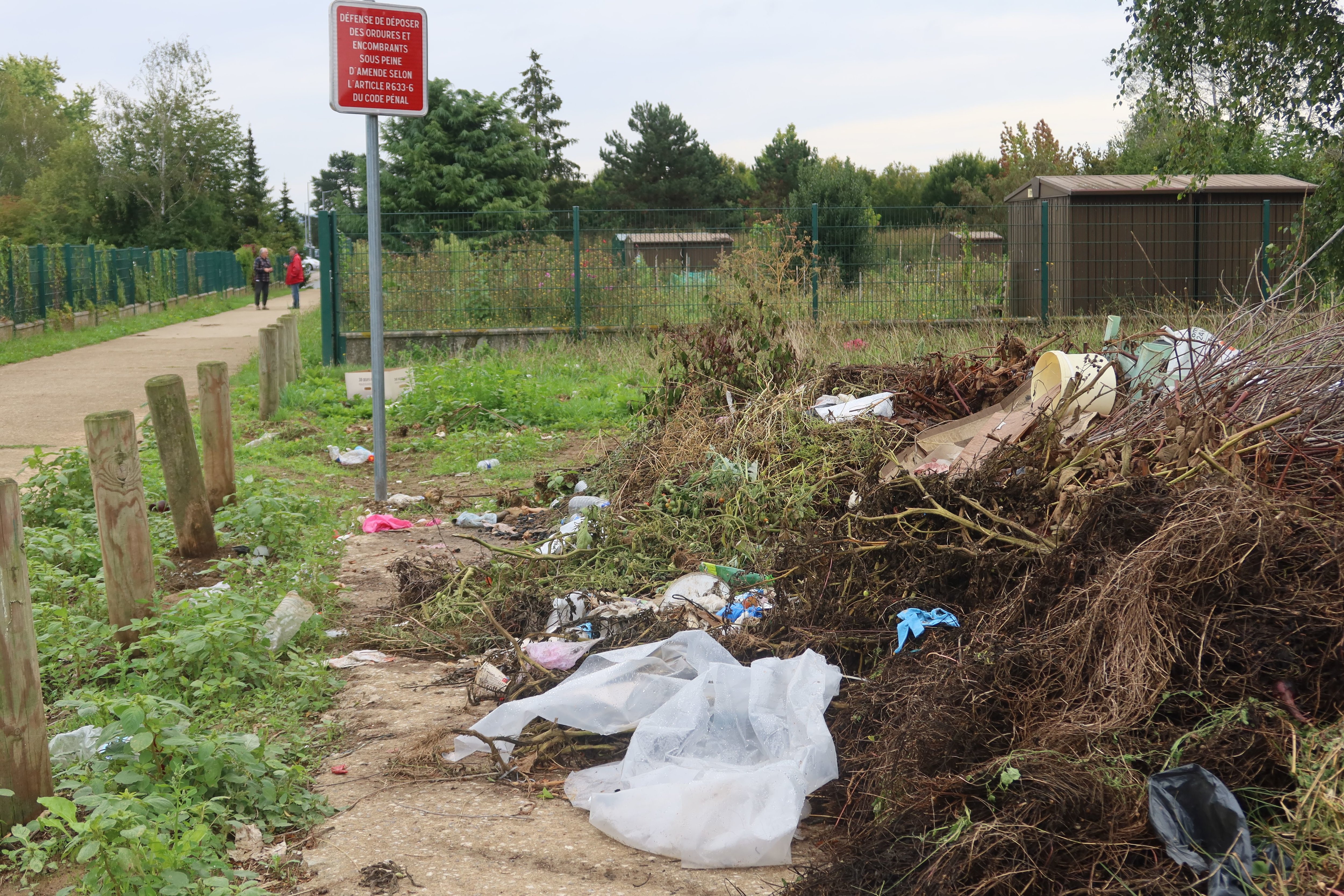 Creil (Oise), le 11 septembre. Plastique, matériaux mêlés aux déchets verts... Les jardins familiaux font régulièrement l'objet de dépôts sauvages, même au pied du panneau d'interdiction situé à l'entrée. LP/Florent Heib