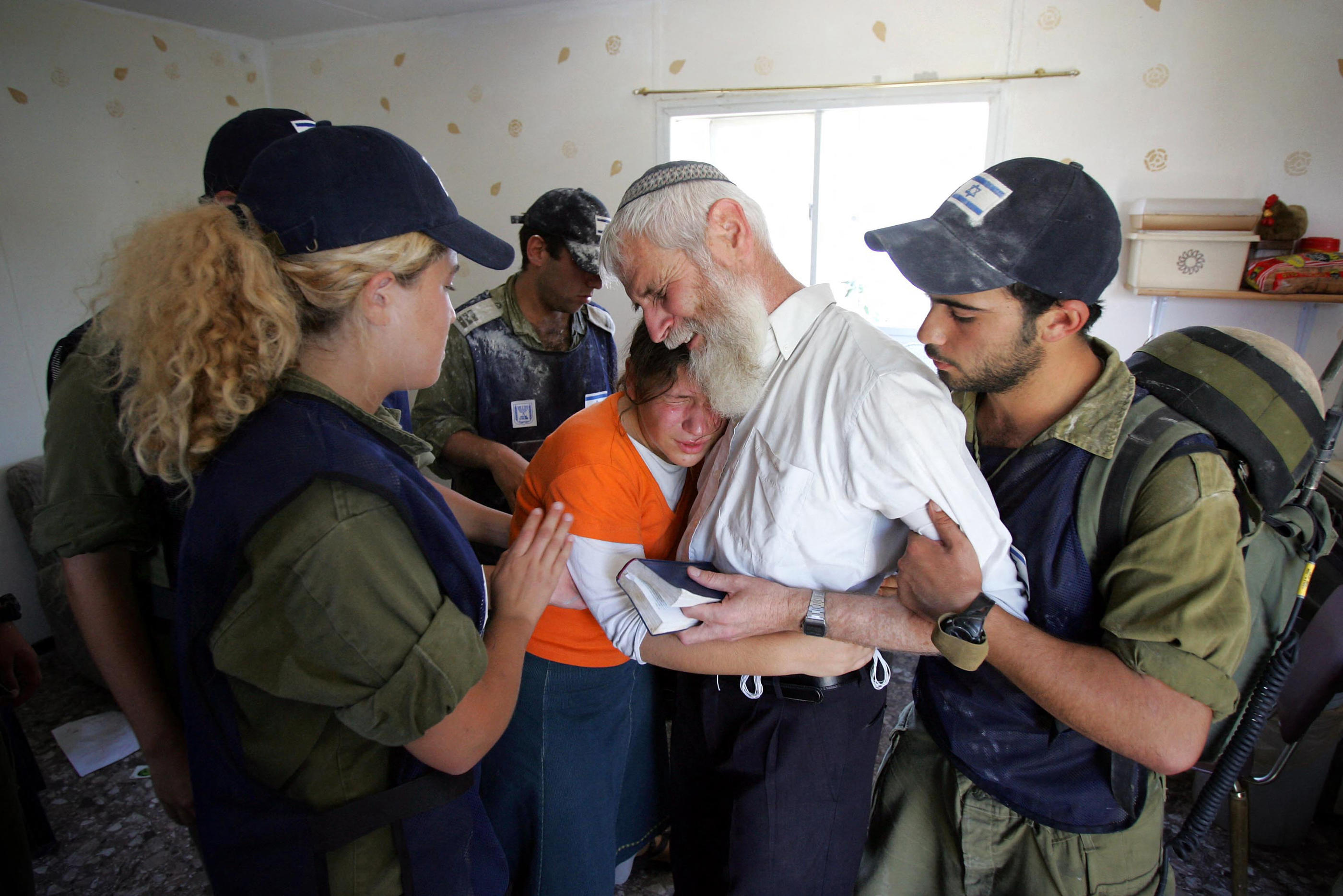 Des habitants de la colonie de Kfar Darom, dans le sud de la bande de Gaza, escortés hors de leur maison par des policiers israéliens, lors du retrait de 2005 ordonné par Ariel Sharon. AFP/David Furst