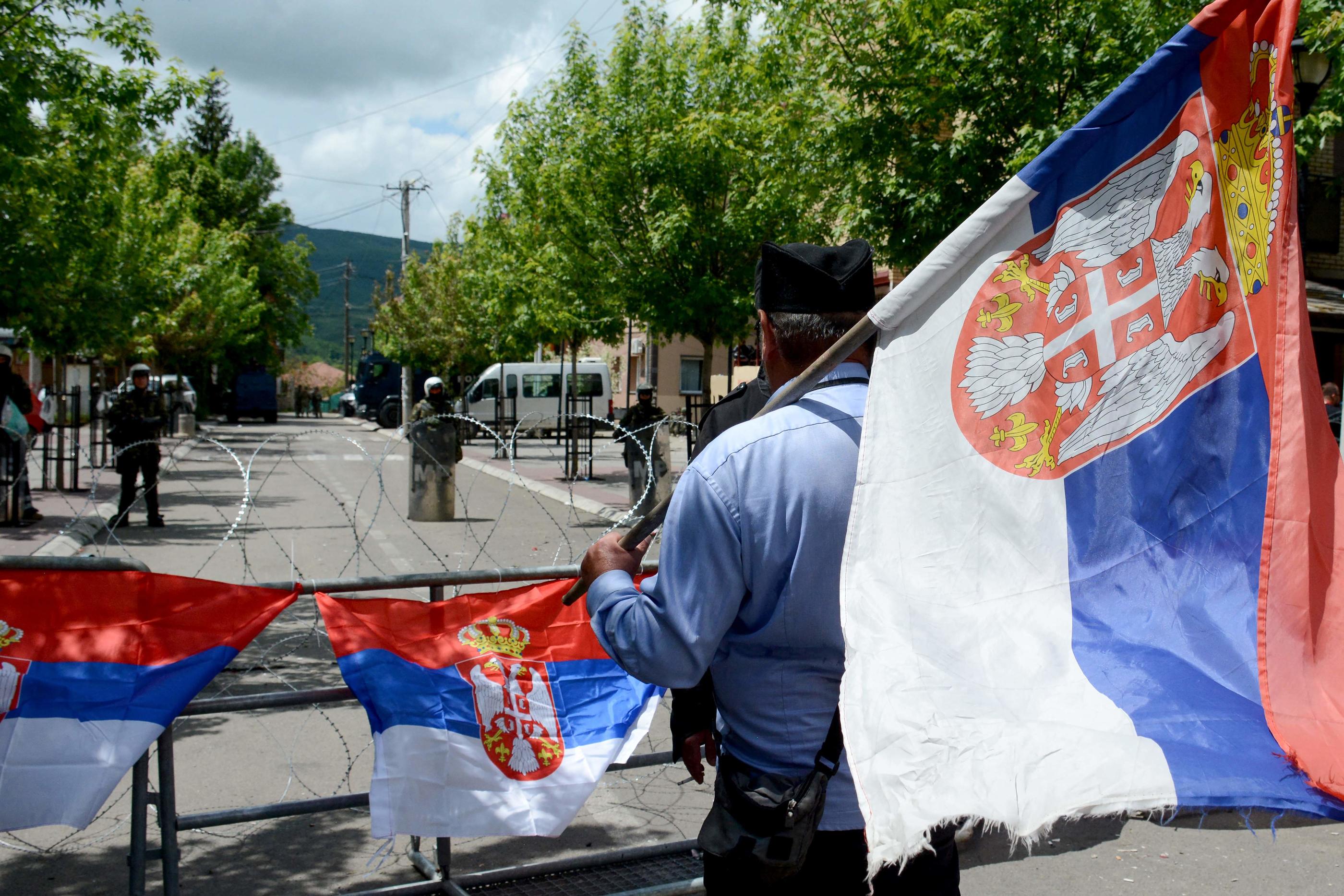 Zvecan, le 31 mai 2023. Un homme tenant un drapeau serbe se place devant des soldats de la Kfor. AFP/Stringer