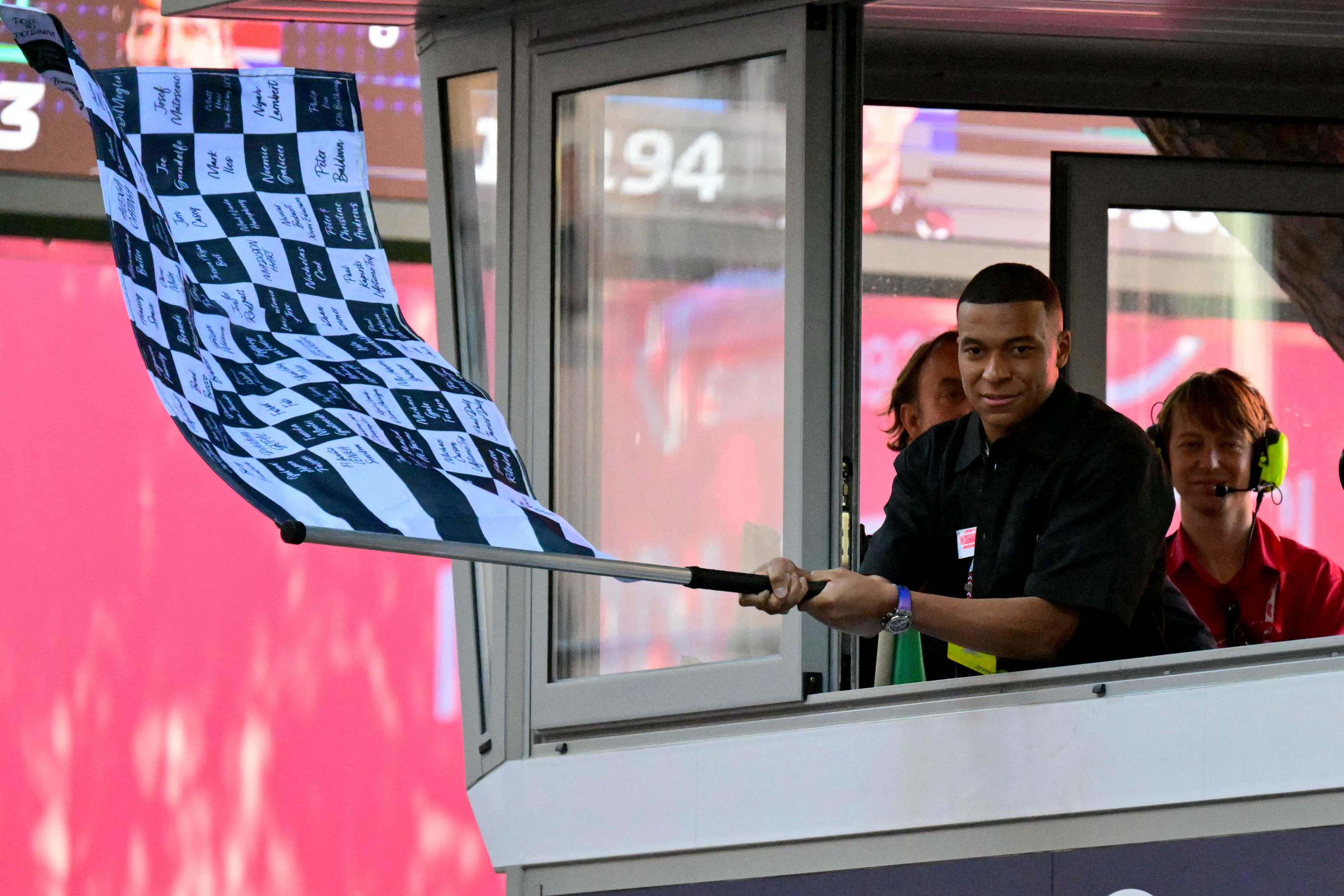 Kylian Mbappé a salué la victoire de Charles Leclerc en agitant le drapeau à damiers pour le vainqueur du GP de Monaco. AFP/ANDREJ ISAKOVIC