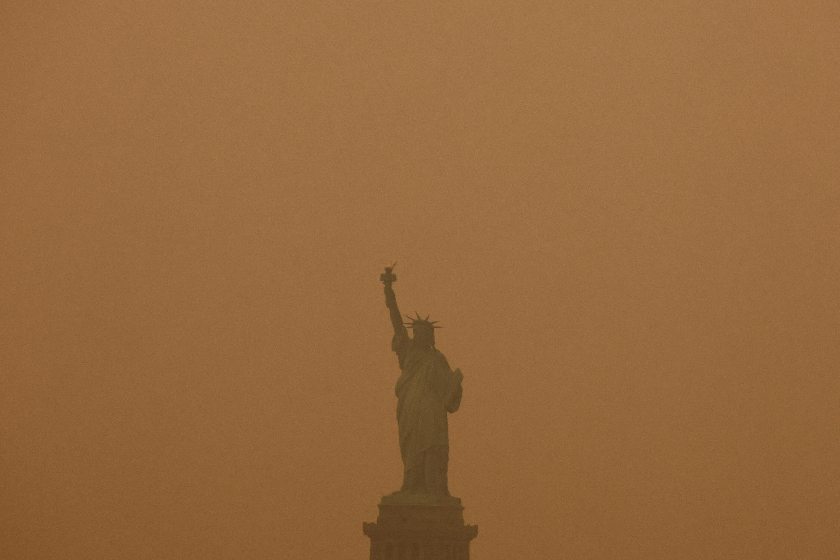 La Statue de la Liberté, comme tout New York, est recouverte d'une brume orangée provoquée par les feux de forêt au Canada. REUTERS/Amr Alfiky