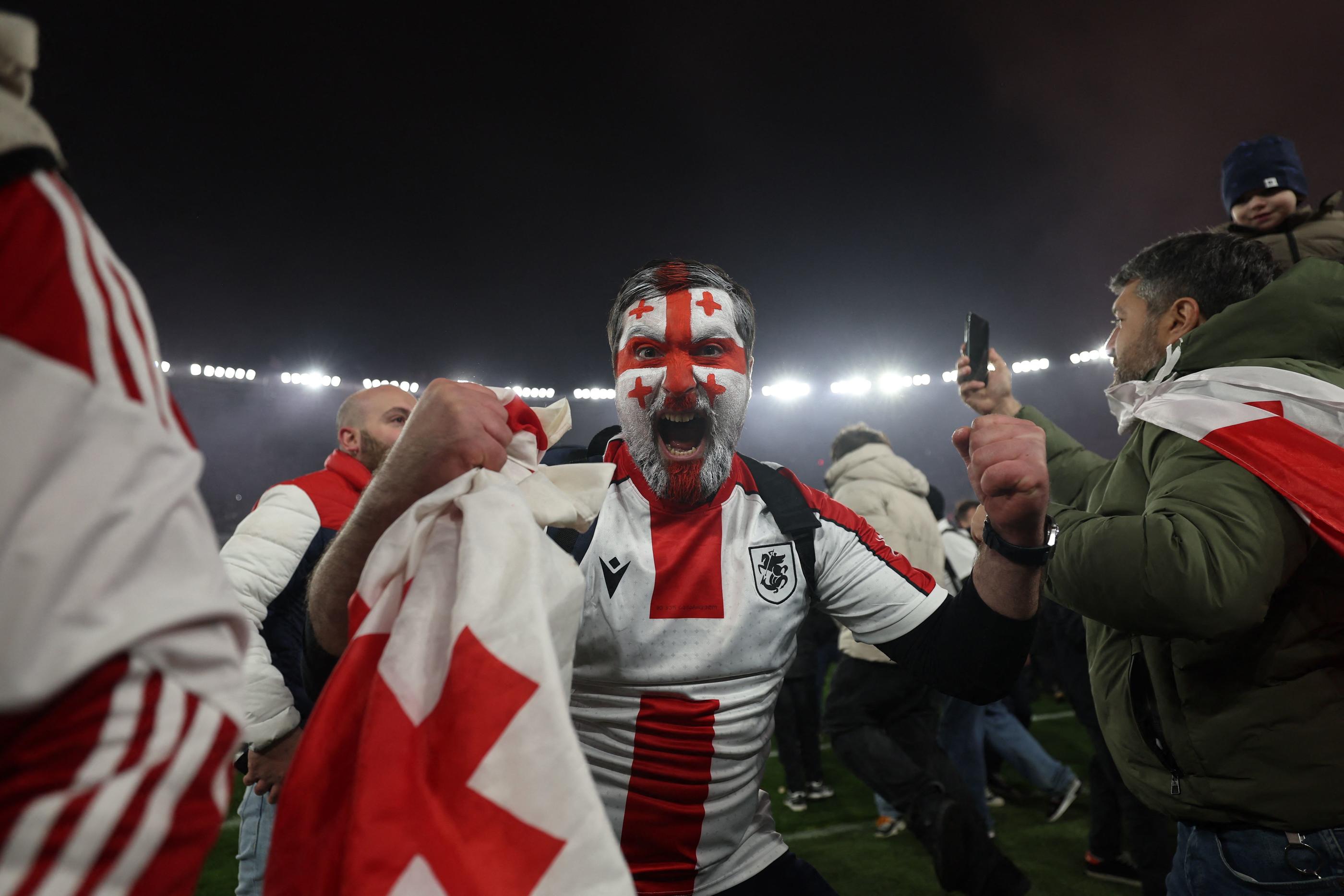 Dès la fin du match, les supporters georgiens ont envahi la pelouse pour fêter la qualification pour l'Euro en Allemagne. (Photo by Giorgi ARJEVANIDZE / AFP)