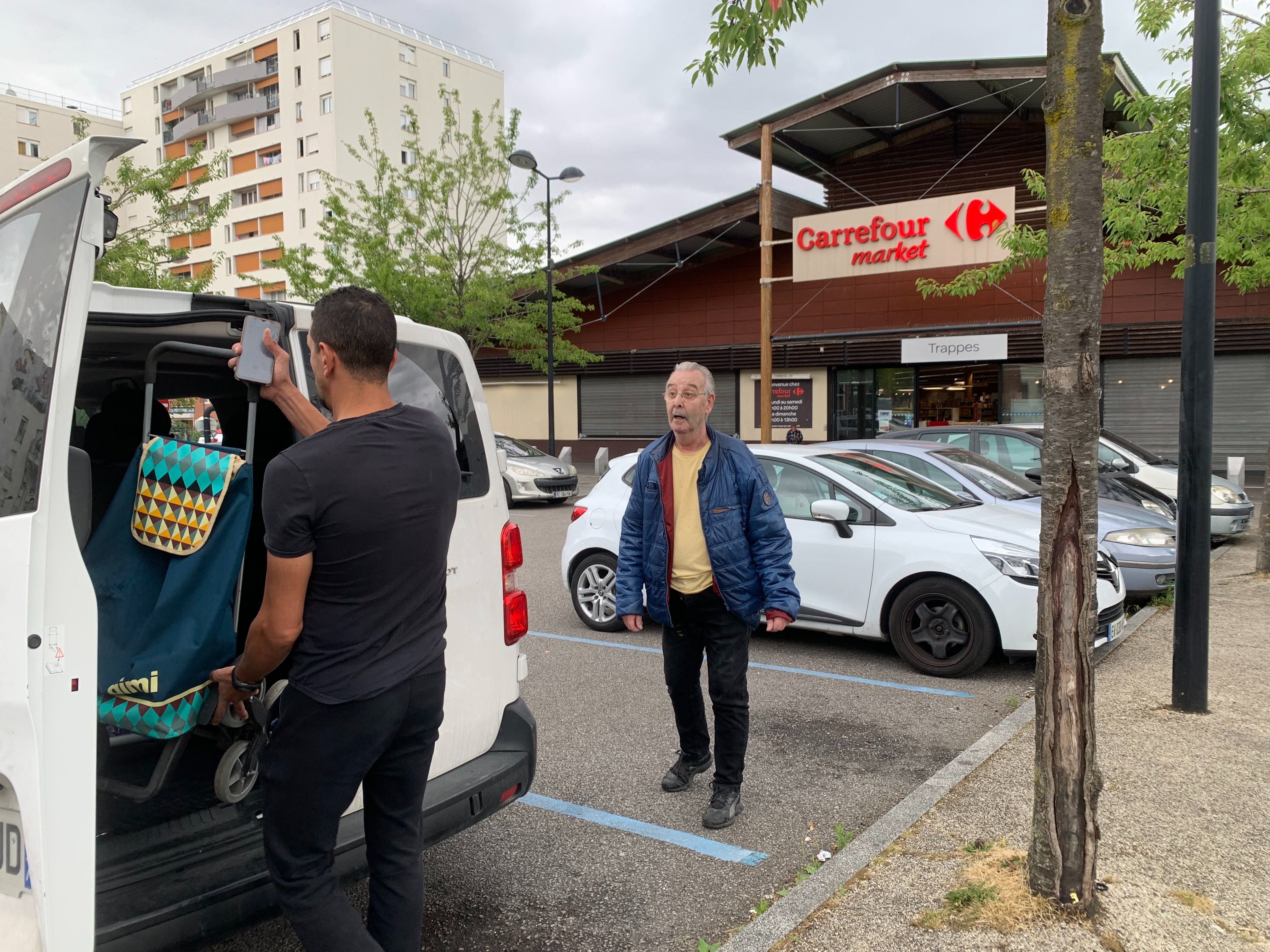 Trappes (Yvelines), ce mardi. Au volant d'un minibus, Fouad (à gauche) assure la navette vers d'autres supermarchés pour les habitants du quartier des Merisiers, comme Michel (à droite). LP/Maxime Laurent