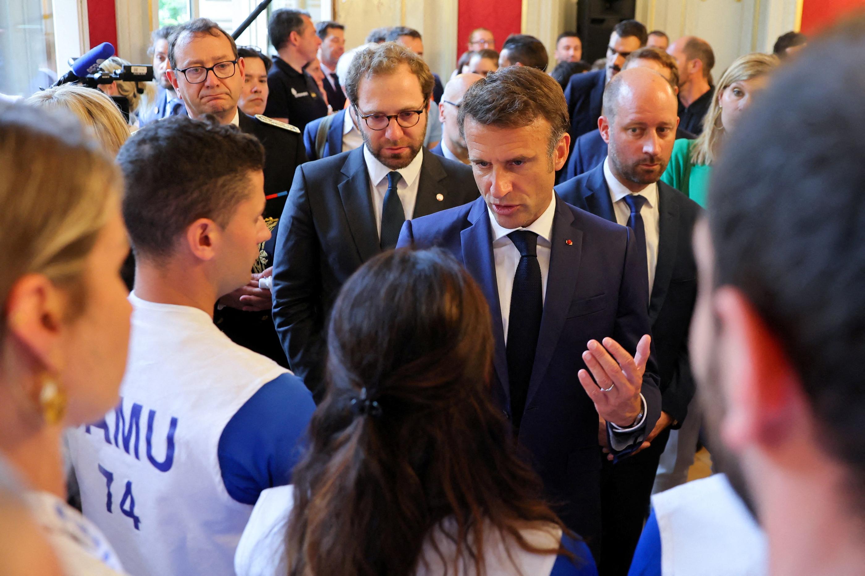 Le président Emmanuel Macron discute avec les secours qui ont pris en charge les victimes de l'attaque d'Annecy. AFP/Denis Balibouse
