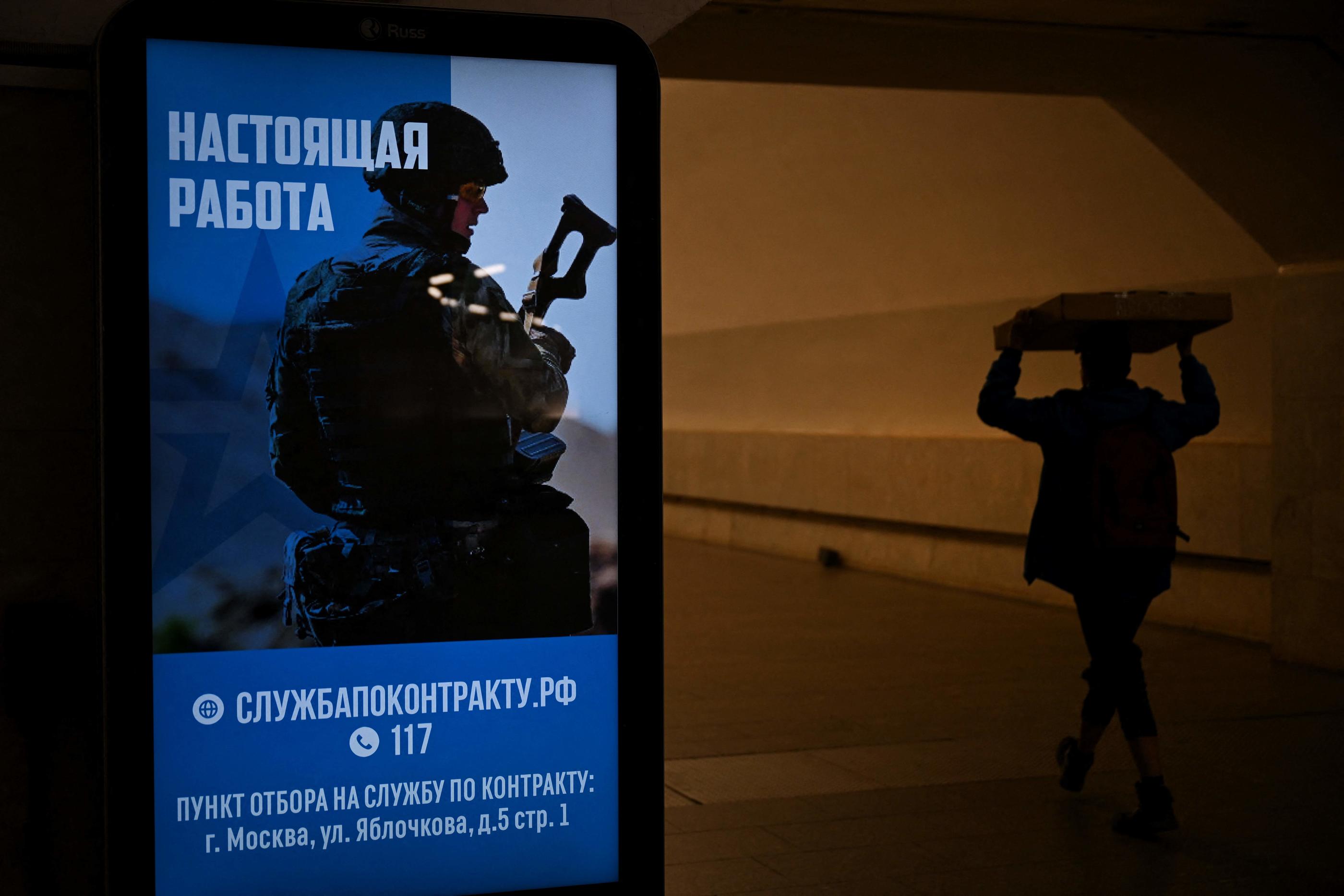 A man walks past an advertising screen promoting contract military service in the Russian army in Moscow on May 11, 2023. (Photo by NATALIA KOLESNIKOVA / AFP)