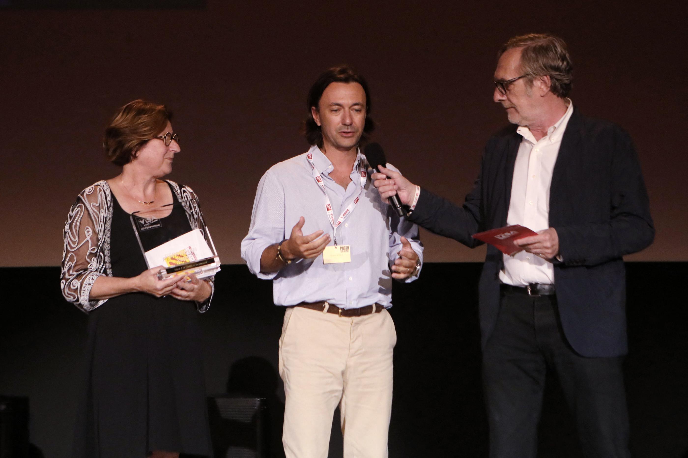 Le photojournaliste italo-britannique Siegfried Modola (au centre) reçoit un Visa d'Or aux côtés d'Hermeline Malherbe, présidente du département des Pyrénées-Orientales et de Jean-François Leroy (à droite), le fondateur de Visa pour l'Image. AFP/ Raymond Roig