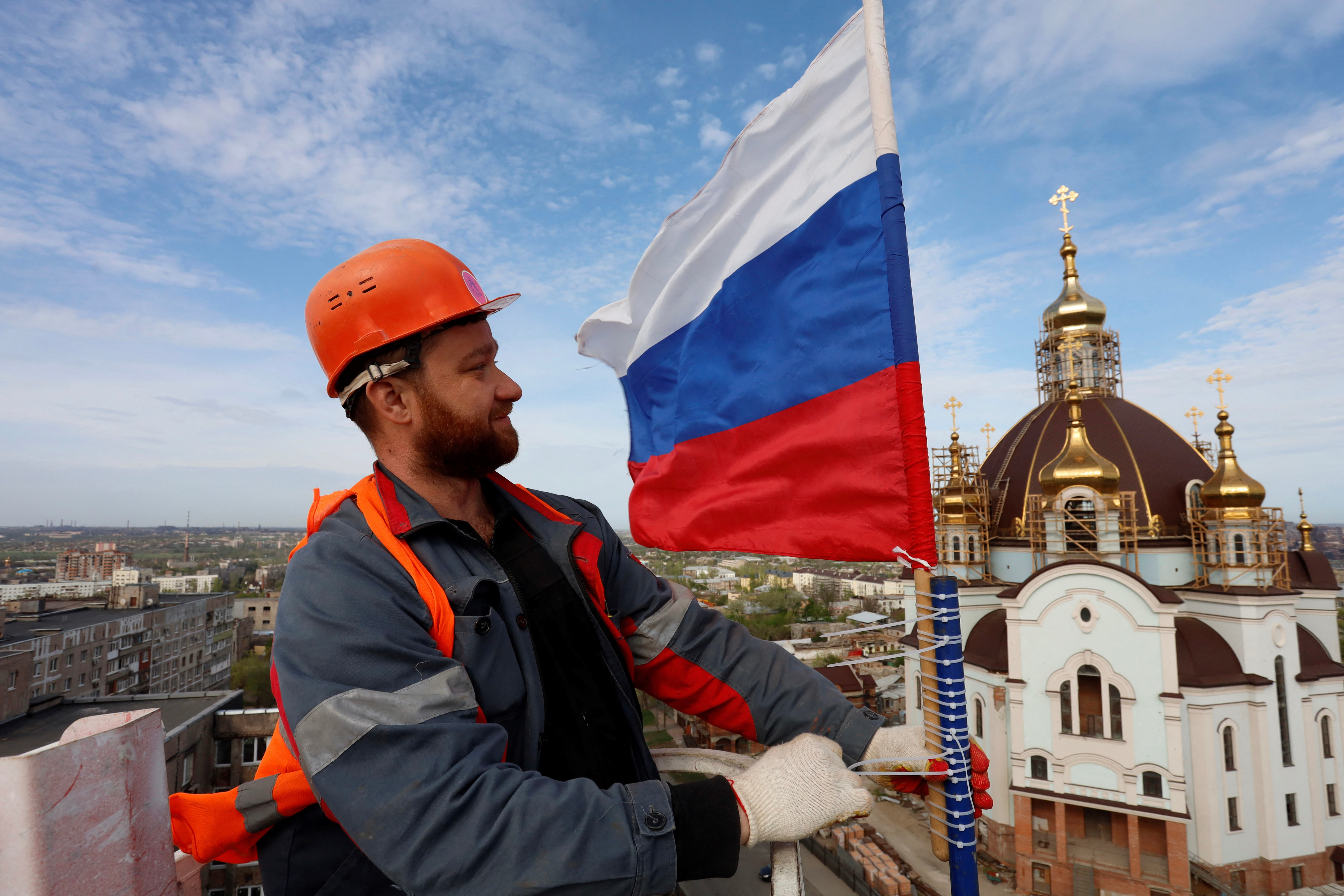 Marioupol, le 17 avril. Un ouvrier du bâtiment attache le drapeau de la Russie au sommet d'un château d'eau dans cette ville sous contrôle russe dans le sud-est de l'Ukraine. AFP