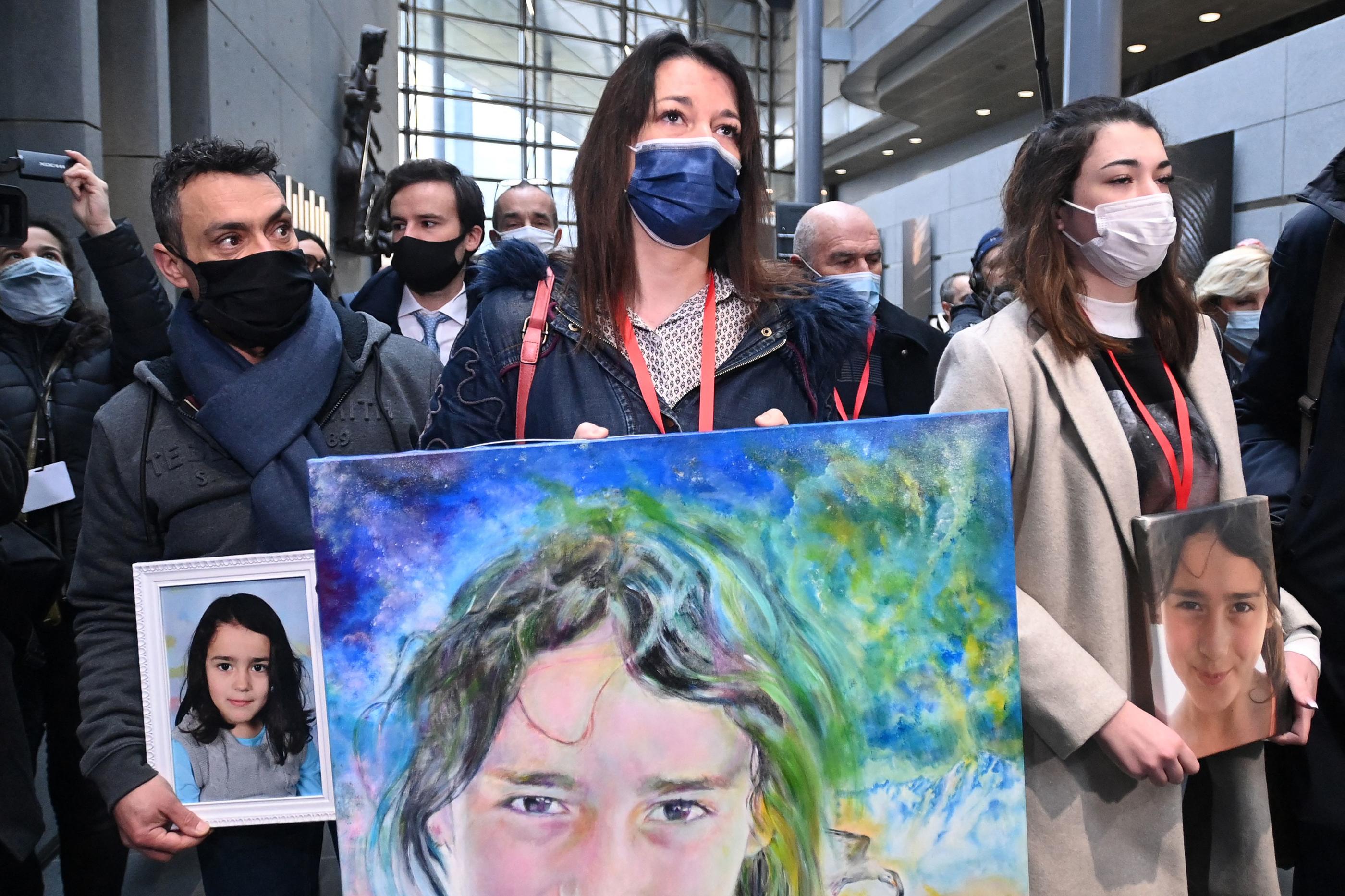 Joachim de Araujo et Jennifer Cleyet-Marrel, parents de Maëlys, et leur fille aînée Colleen, arrivent au tribunal avec des portraits de la fillette, ce lundi matin. AFP/Olivier CHASSIGNOLE