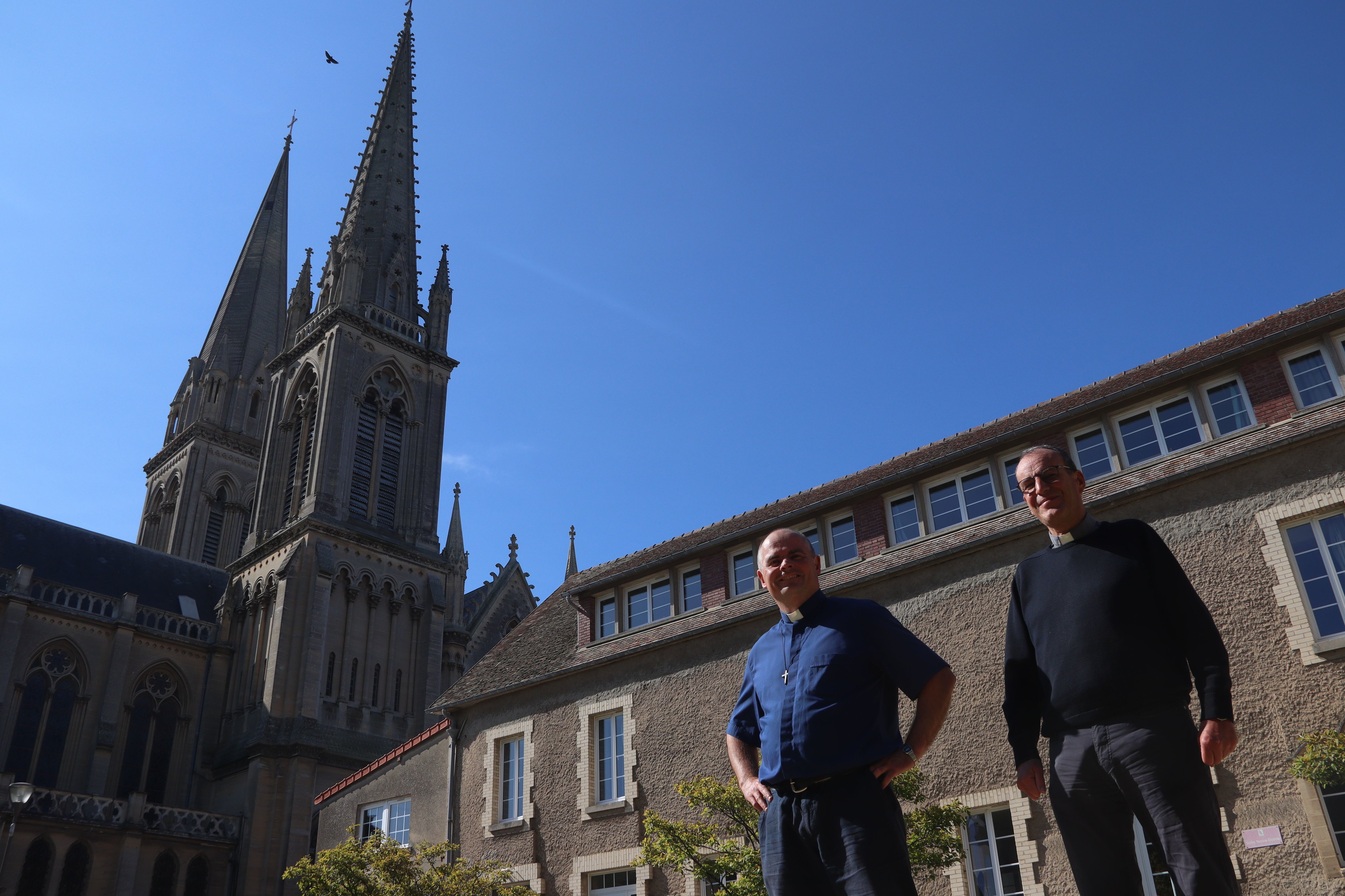 Les prêtres François Lecrux et Laurent Berthout au pied de la Basilique de Douvres-la-Délivrande. A l'initiative de ce dernier, une coach en entreprise accompagne la paroisse pour améliorer son fonctionnement. LP/Esteban Pinel