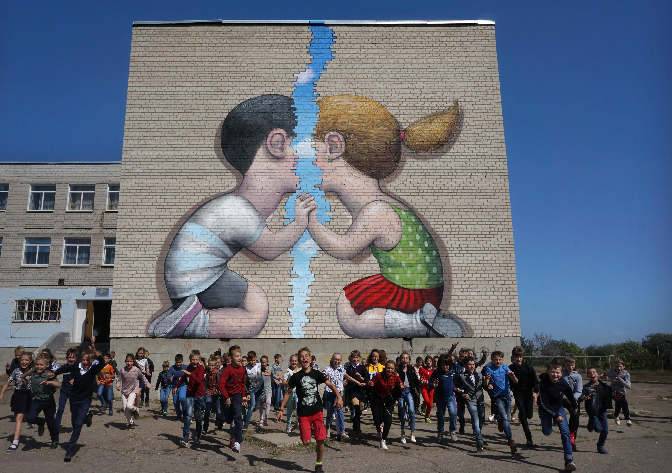Popasna (Ukraine), en 2019. Le street artist Seth a aidé les enfants de l'école n°1 de la ville du Donbass à créer cette fresque dans le cadre du projet «Back to School ! Ukraine». Seth Dans