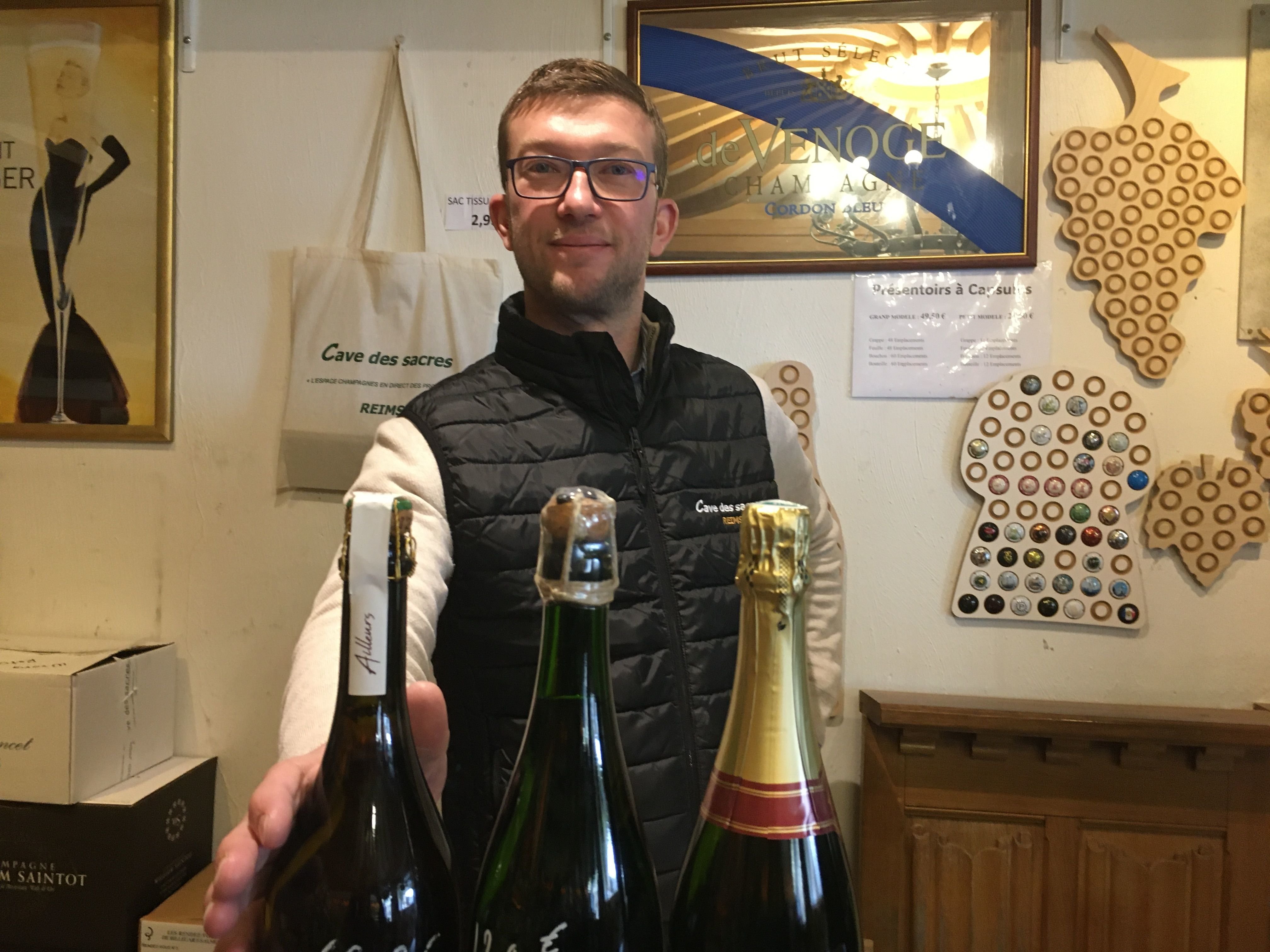 Alexandre Boissel, gérant de la Cave des sacres, à Reims (Marne) présente différents modèles possibles de bouteilles de champagne : avec une bandelette (à gauche), avec une ficelle cachetée à la cire (au milieu) et avec la traditionnelle coiffe métallique (à droite). LP/Marie Blanchardon