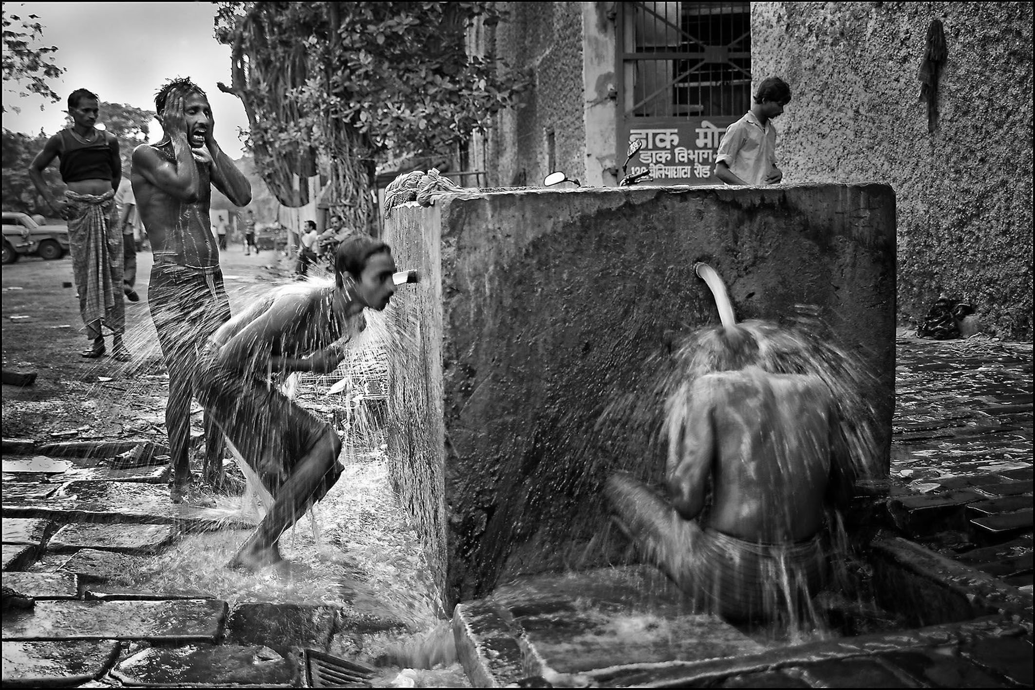 Inde, Calcutta. Scène courante où les résidents des quartiers périphériques sans approvisionnement en eau se lavent dans la rue :  une des photos exposées au festival Visa pour l'image de Perpignan © Ian Berry / Magnum Photos